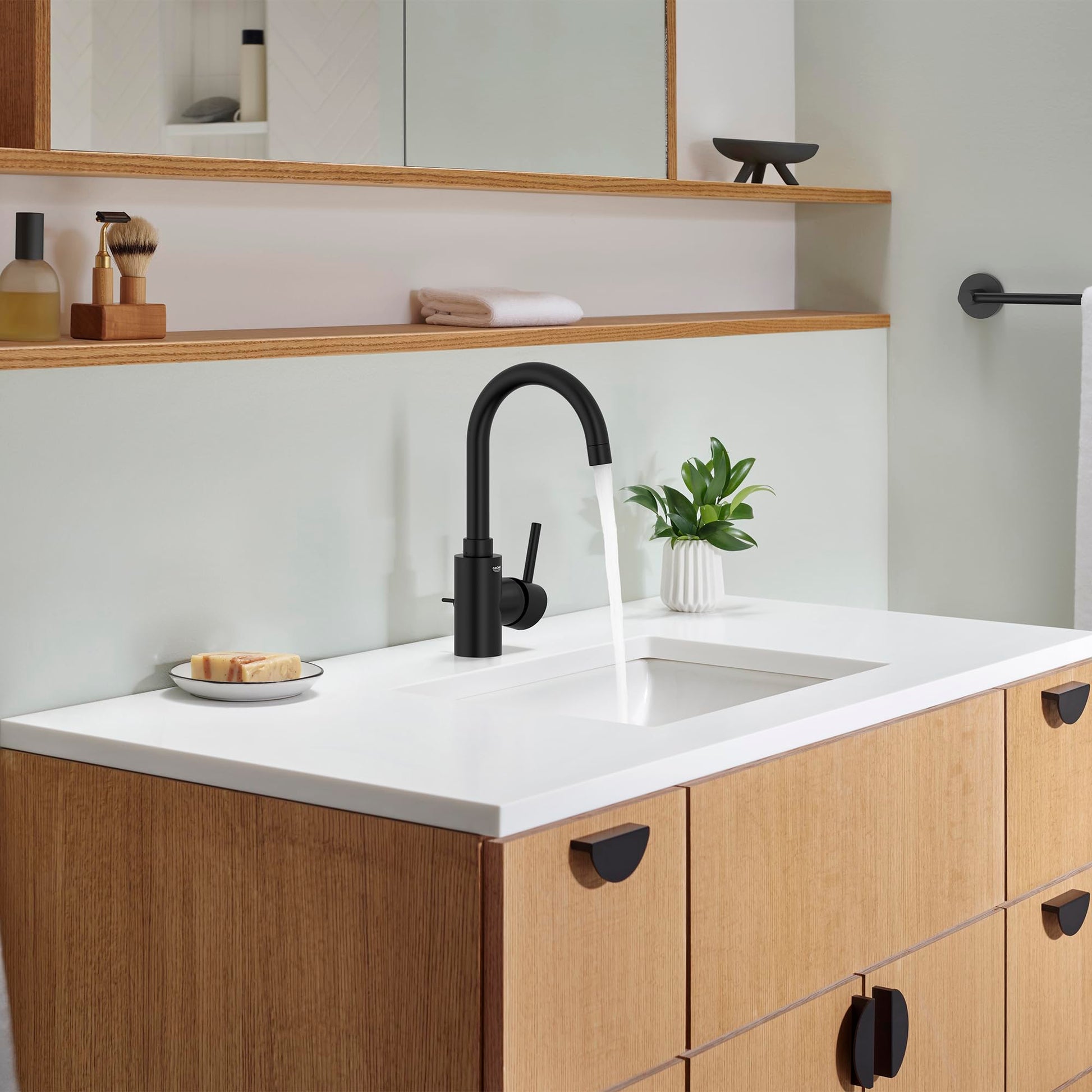 Matte black single-handle bathroom faucet with curved spout installed on white countertop above wooden vanity.