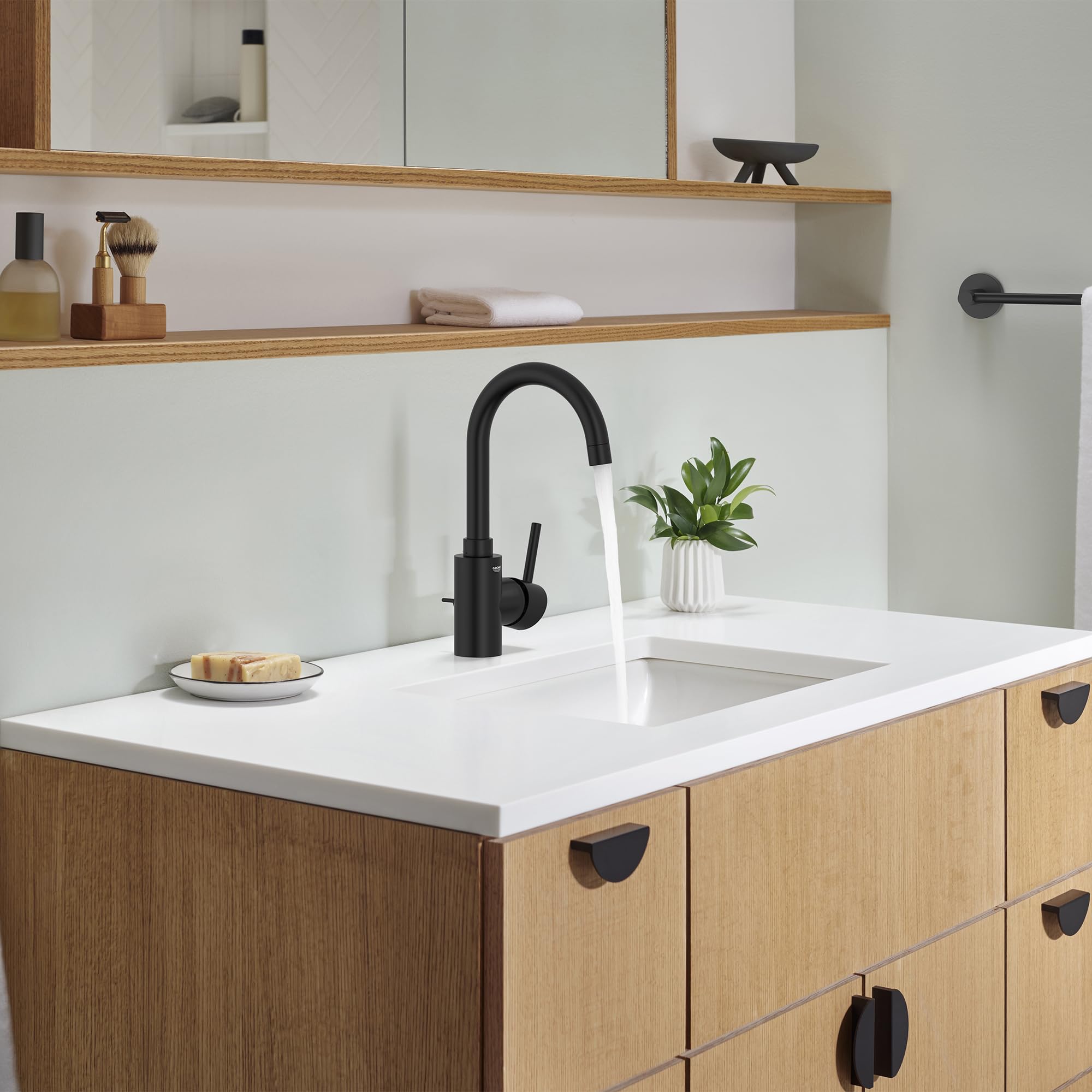 Matte black single-handle bathroom faucet with curved spout installed on white countertop above wooden vanity.