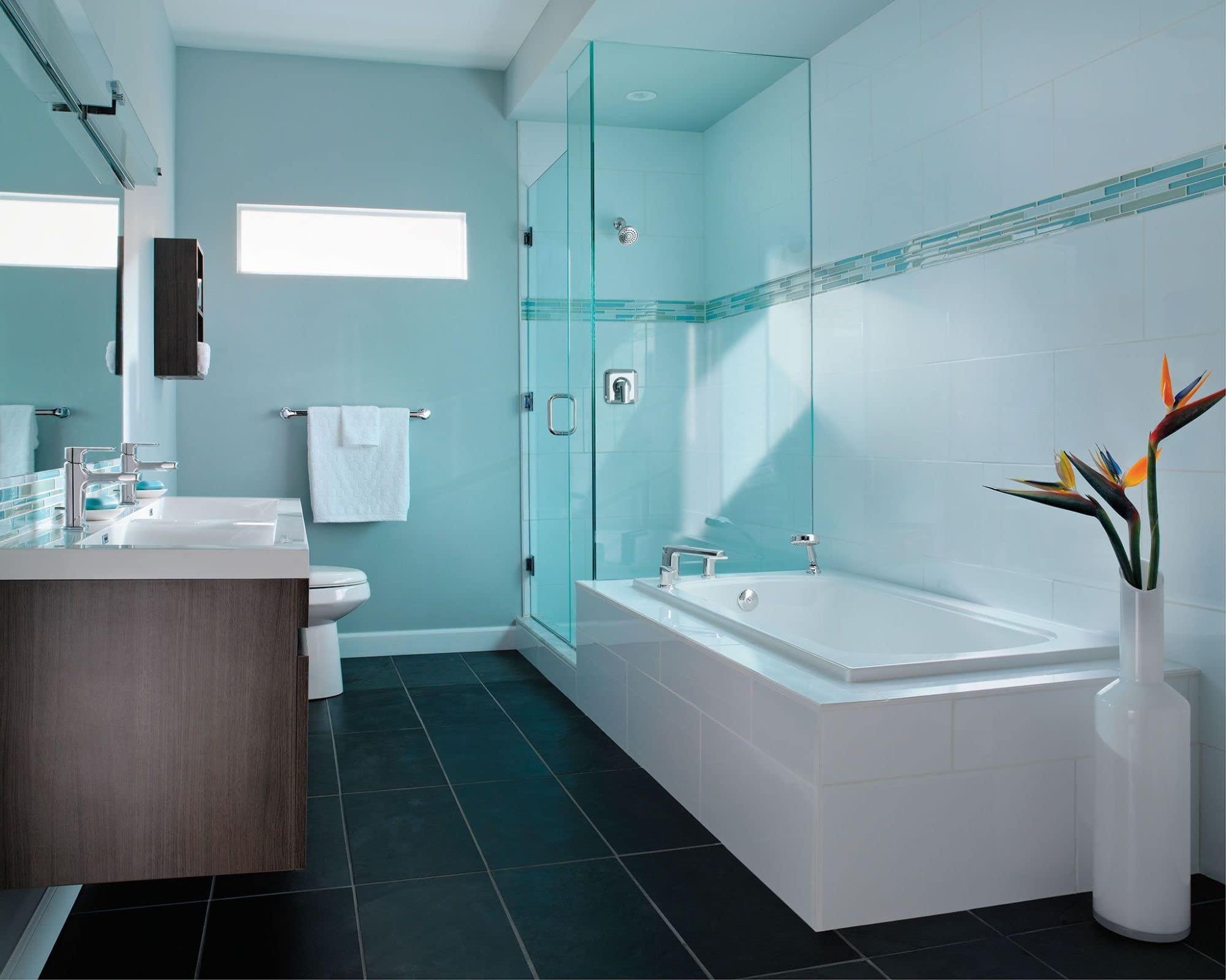 Chrome two-handle low arc faucet with hand shower mounted on white rectangular bathtub in bathroom.