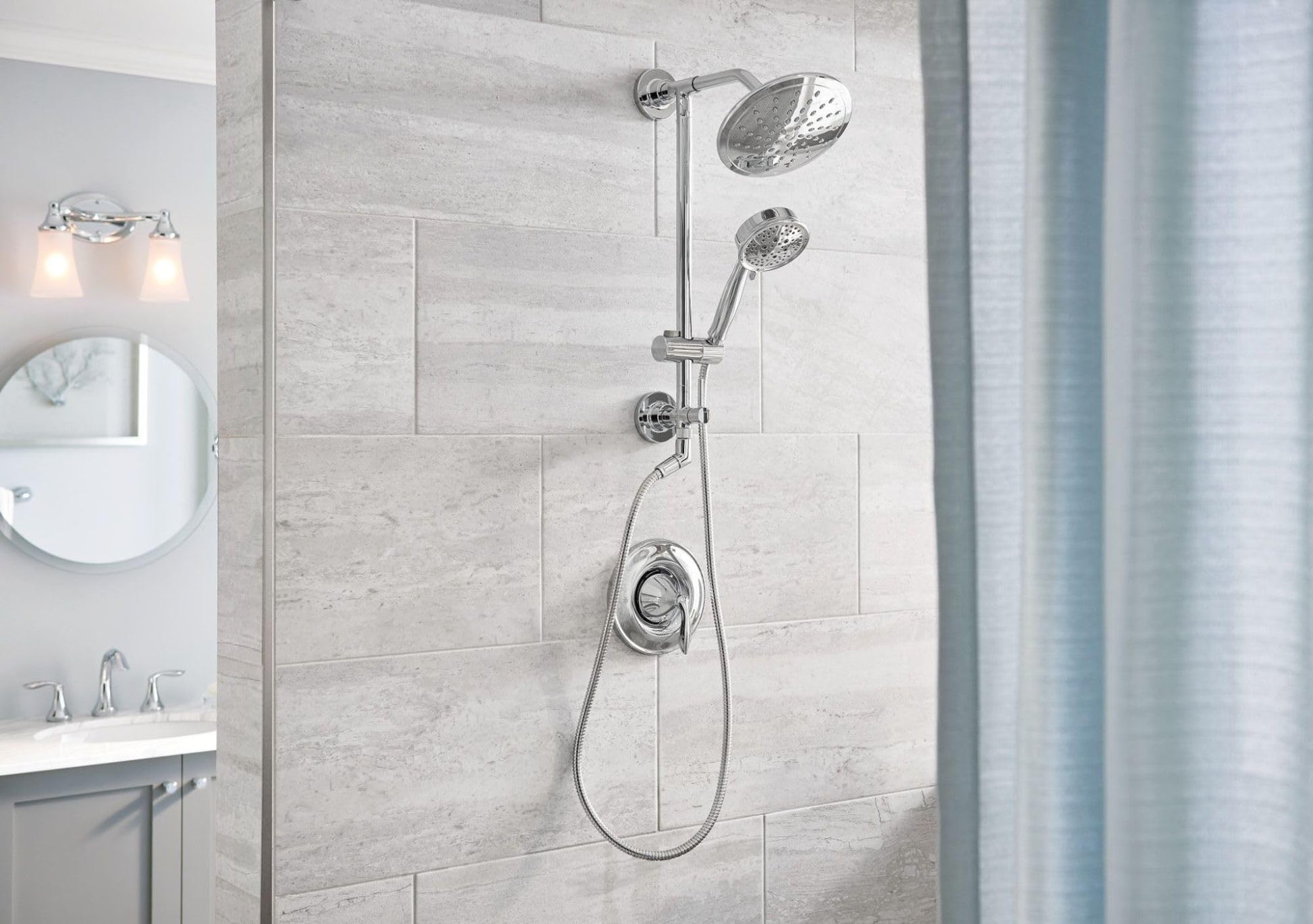Chrome shower system with large rainshower showerhead and handheld showerhead mounted on tile wall.