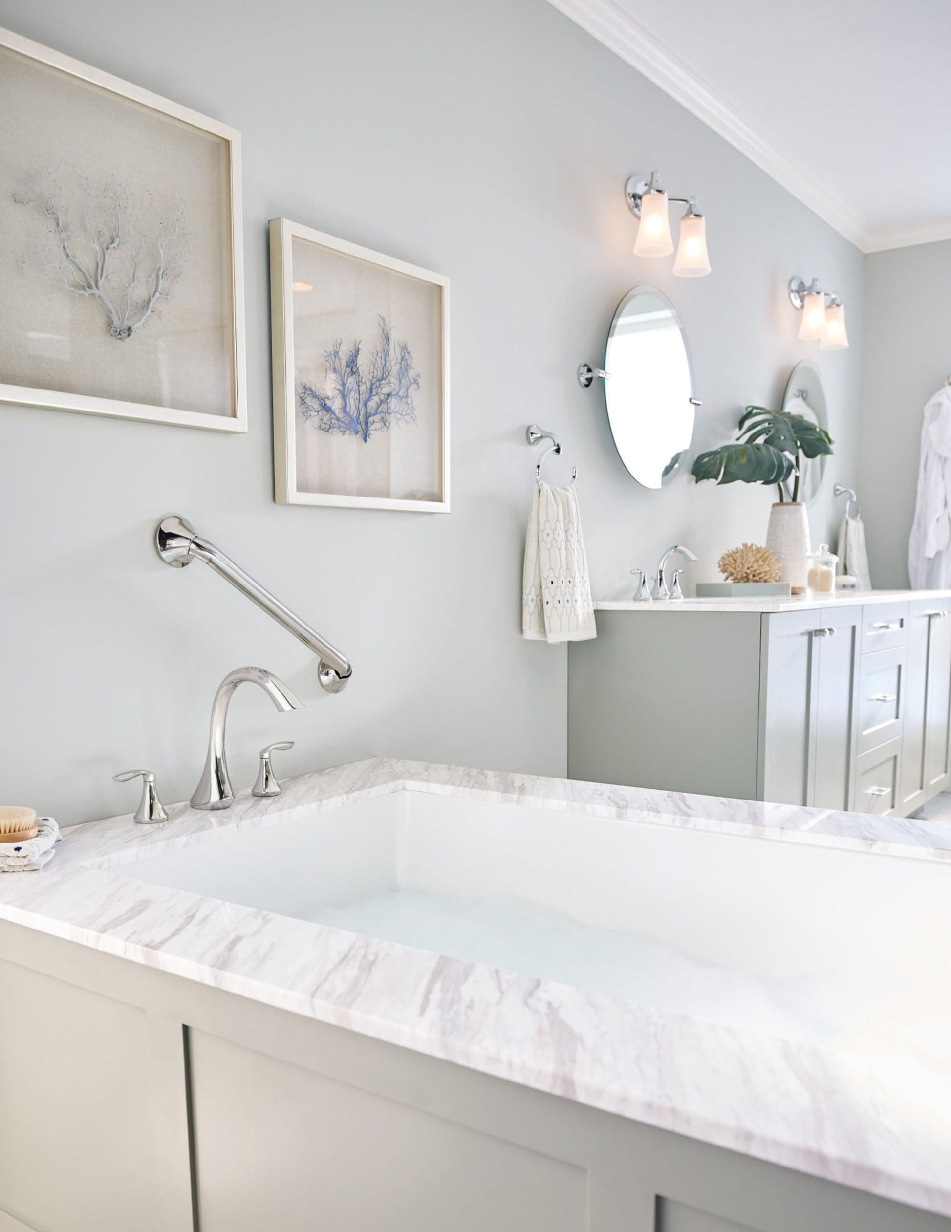 Chrome grab bar mounted horizontally on white bathroom wall above bathtub edge.
