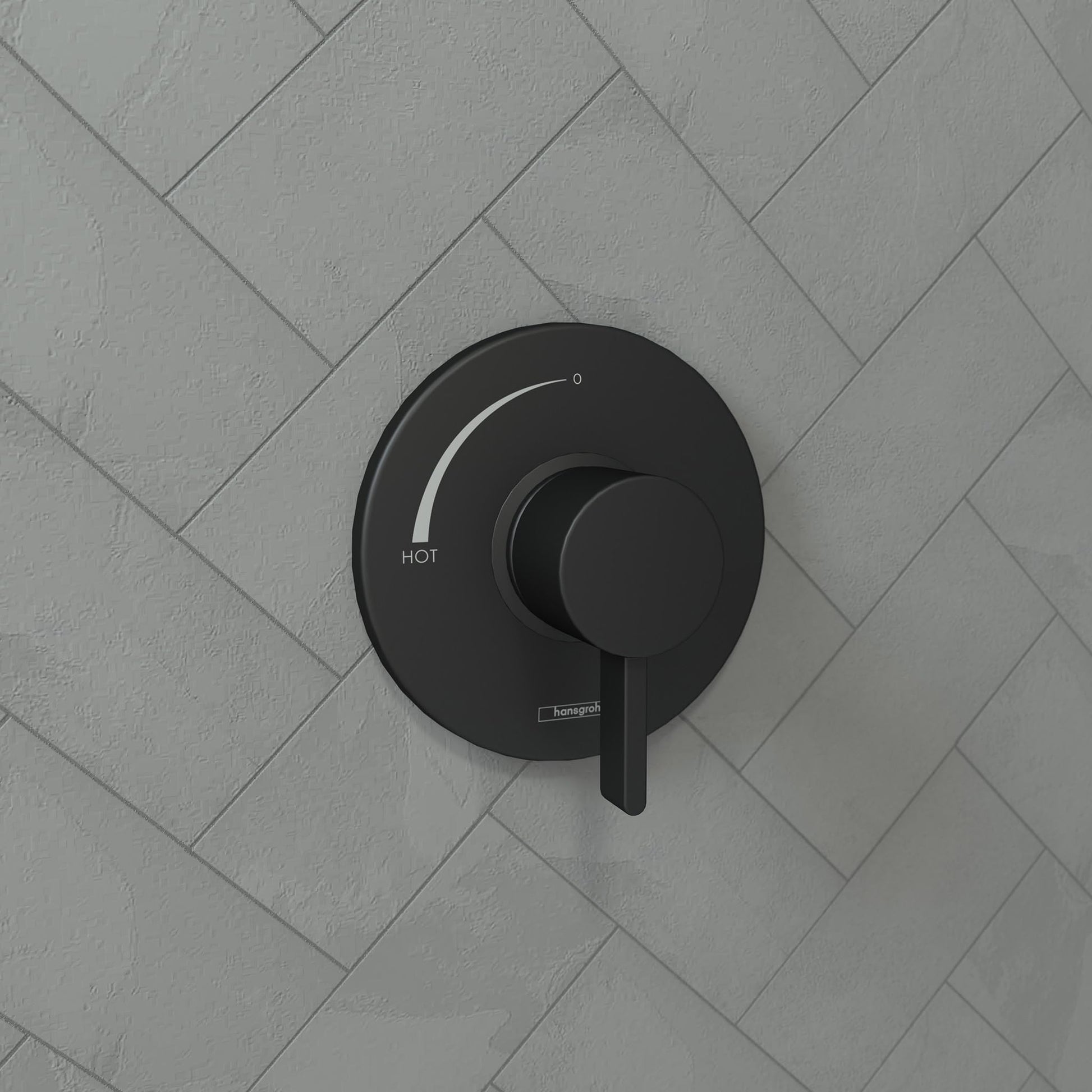 Matte black round pressure balance trim with circular handle and temperature adjustment dial mounted on herringbone tile wall