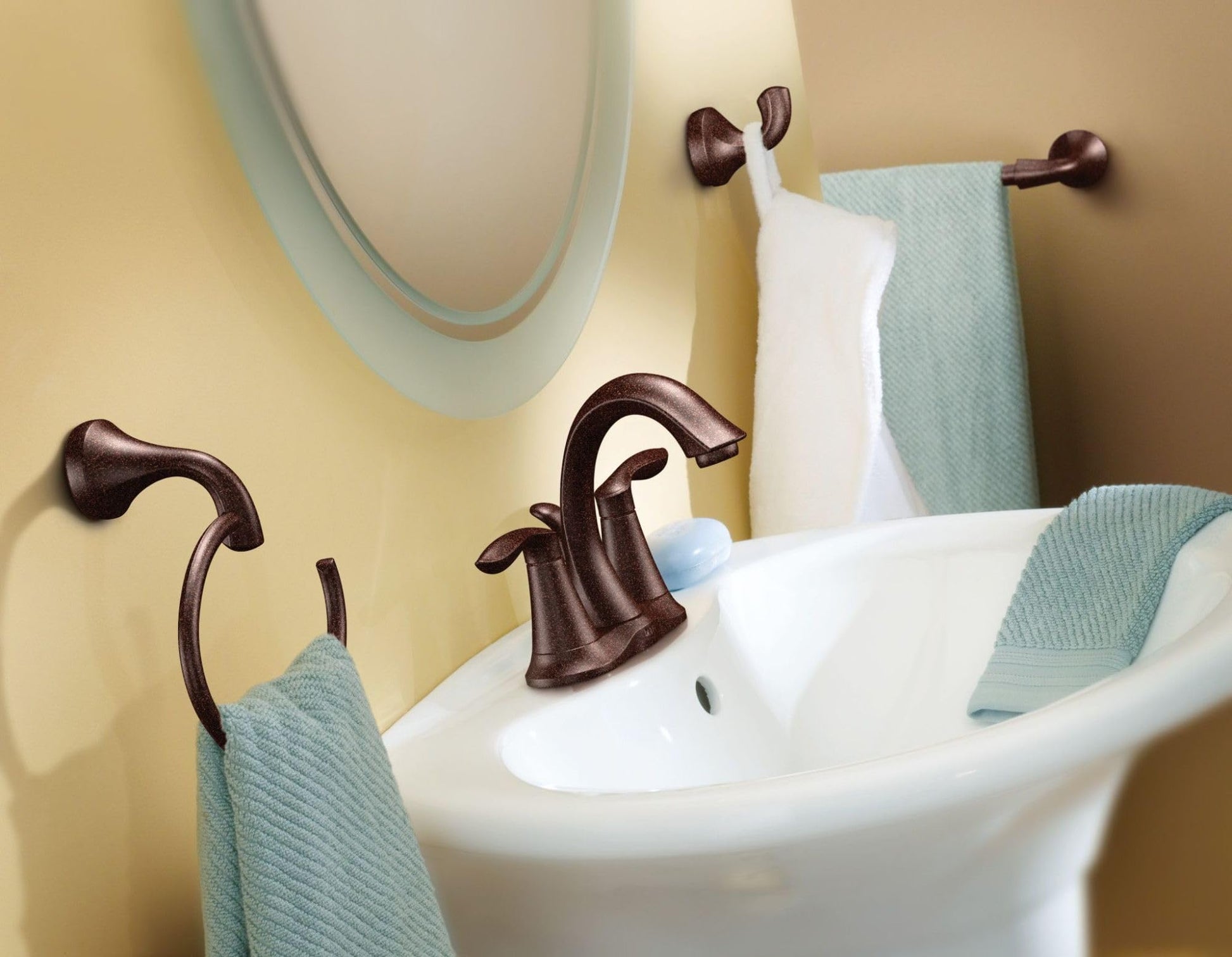 Oil rubbed bronze robe hook with curved hook design mounted on bathroom wall above sink.