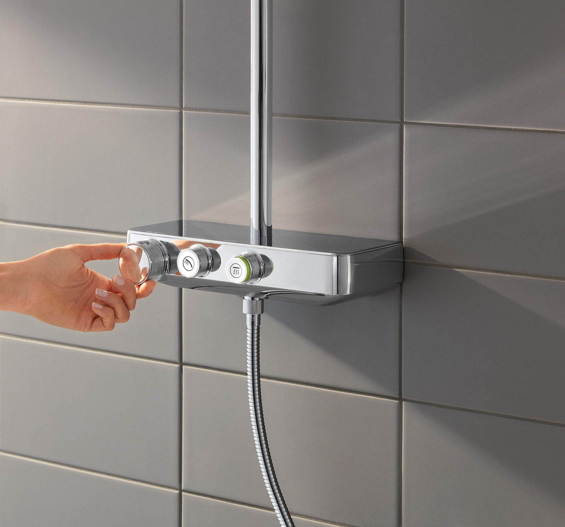Chrome thermostatic shower system with control handles mounted on tile wall and flexible hose connection.