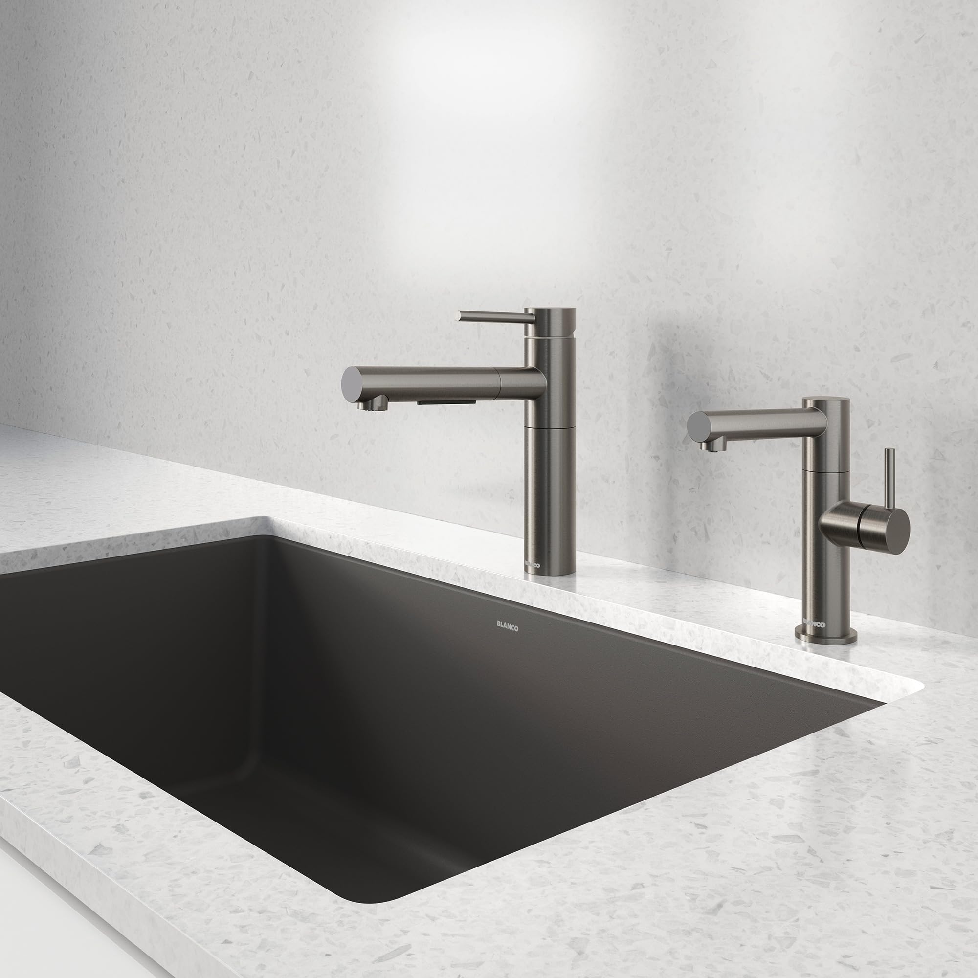 Satin dark steel pull-out kitchen faucet installed above a black rectangular sink on a white marble countertop.