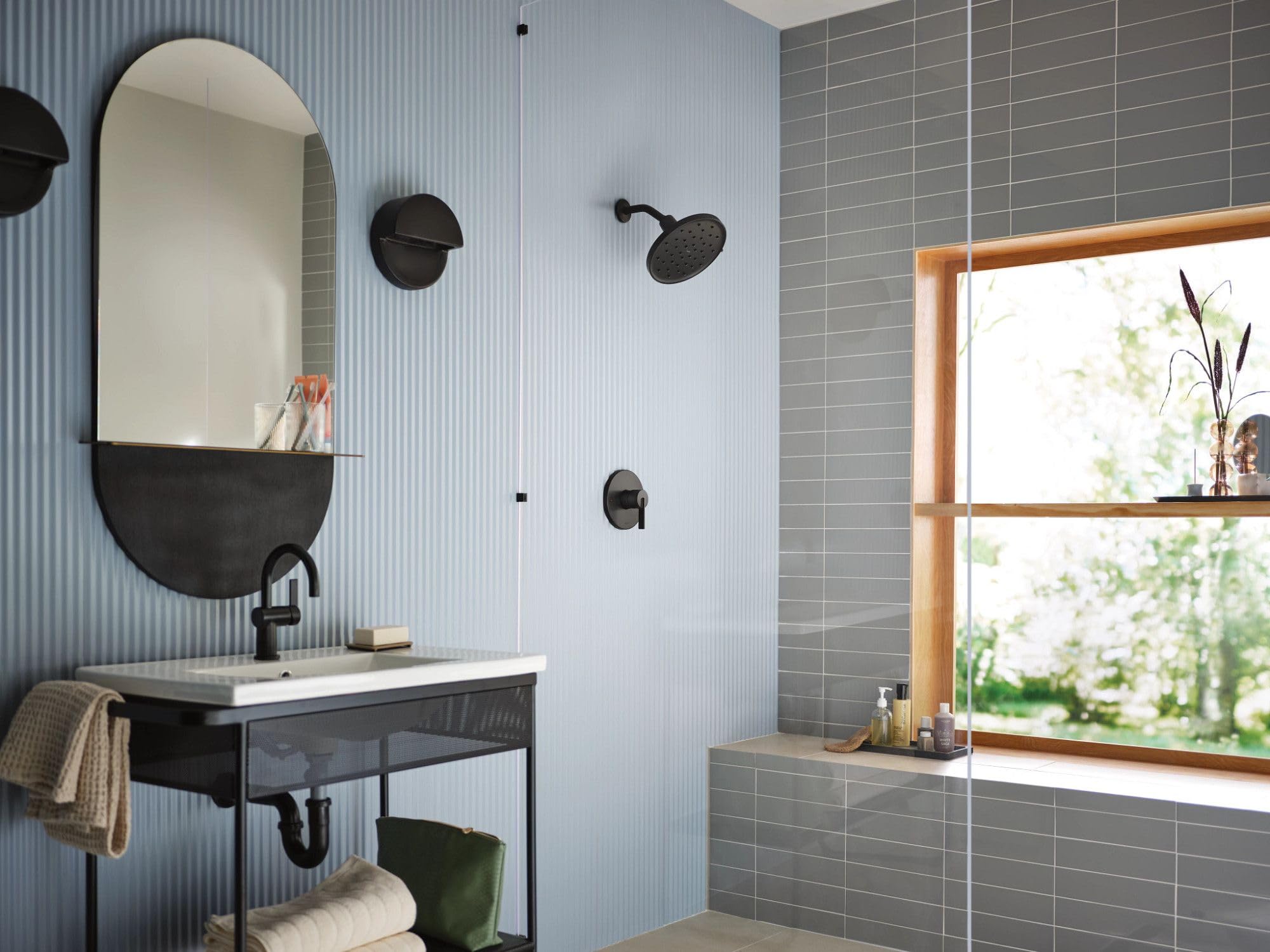 Matte black 9-inch diameter rainshower spray head mounted on shower wall with adjustable arm.