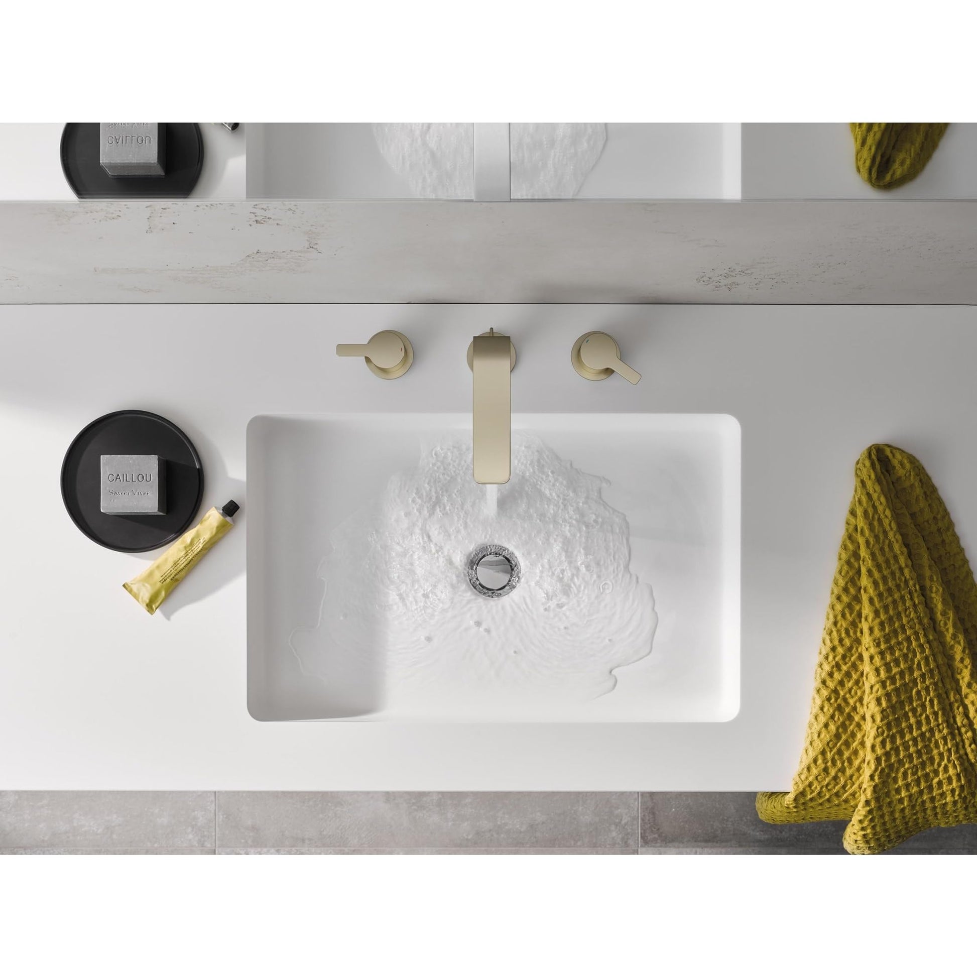 Matte black widespread bathroom faucet with two round handles and vertical spout installed above white rectangular sink.