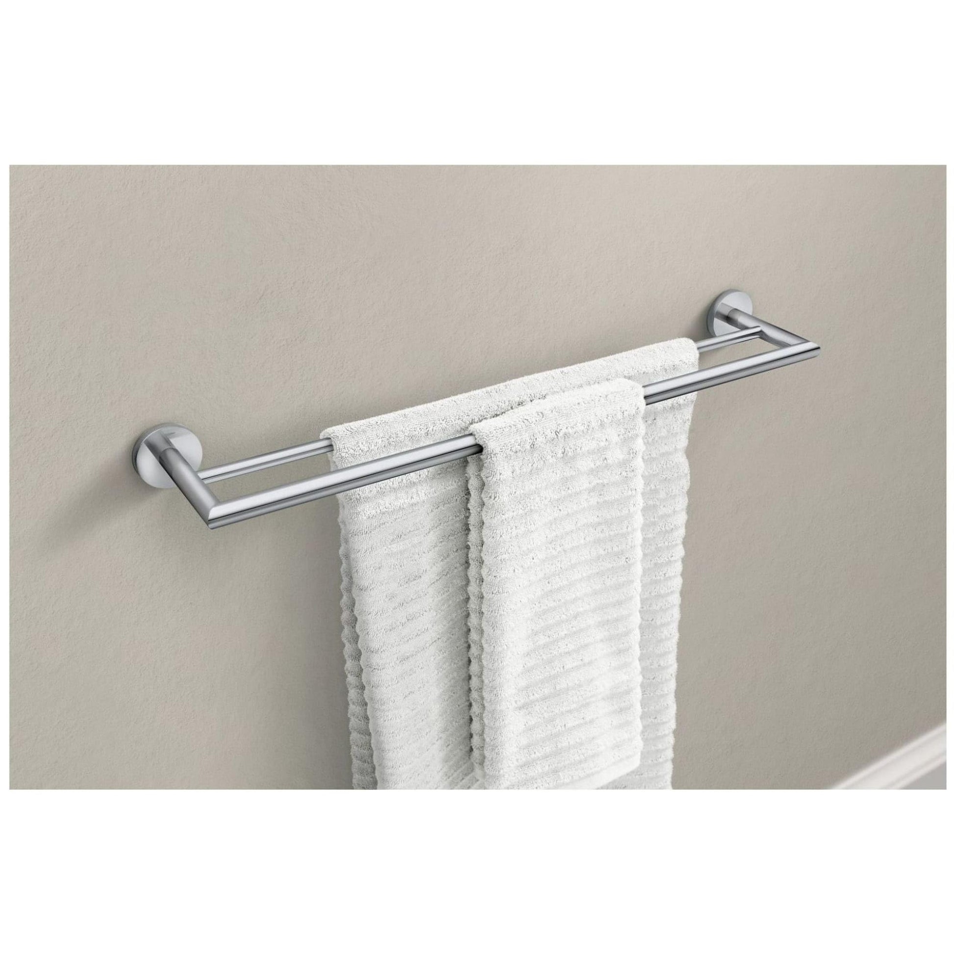 Chrome double towel bar with two parallel rails mounted on beige wall, holding white towels.