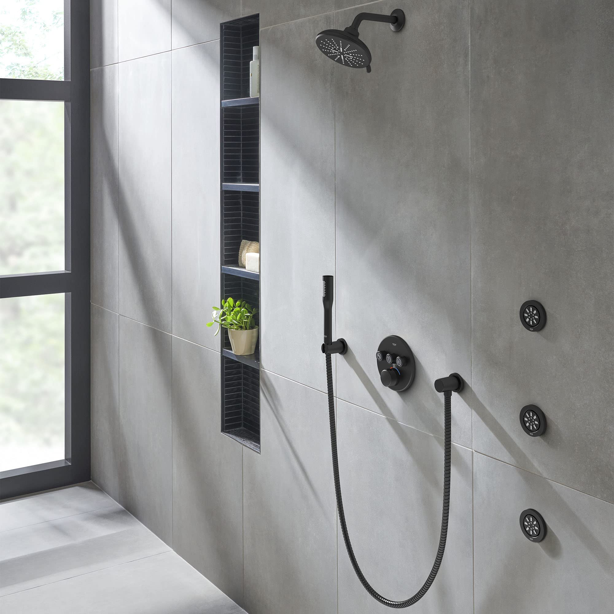 Matte black thermostatic valve trim with overhead rain showerhead, handheld sprayer, and body jets installed in shower wall.