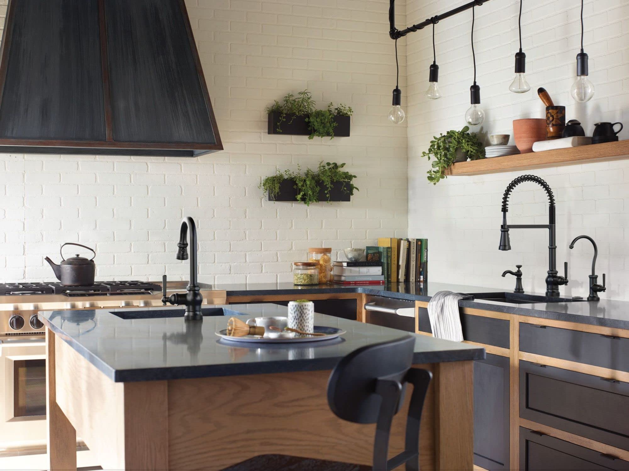 Matte black deck-mounted kitchen soap dispenser with curved spout installed on countertop near sink.