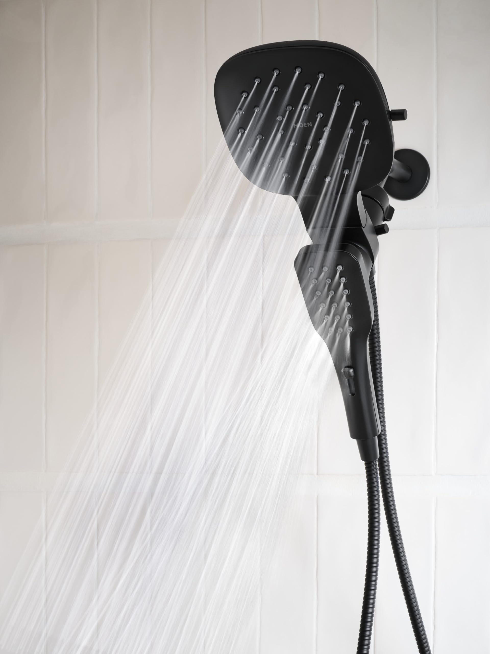 Matte black square rain shower head with water spray and detachable hand shower on flexible hose.