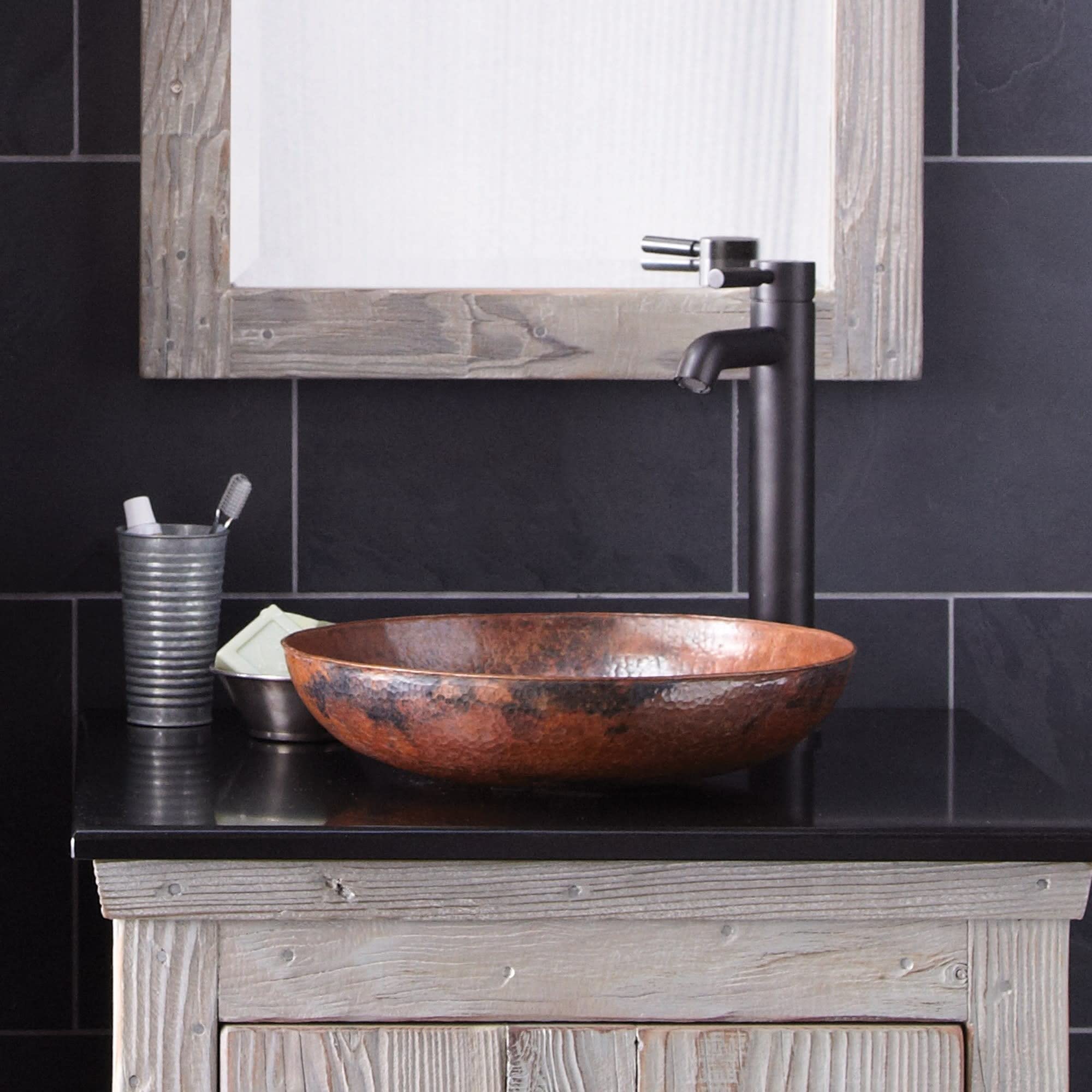 Hammered copper vessel sink with wide oval bowl and textured surface on bathroom vanity with tall faucet.