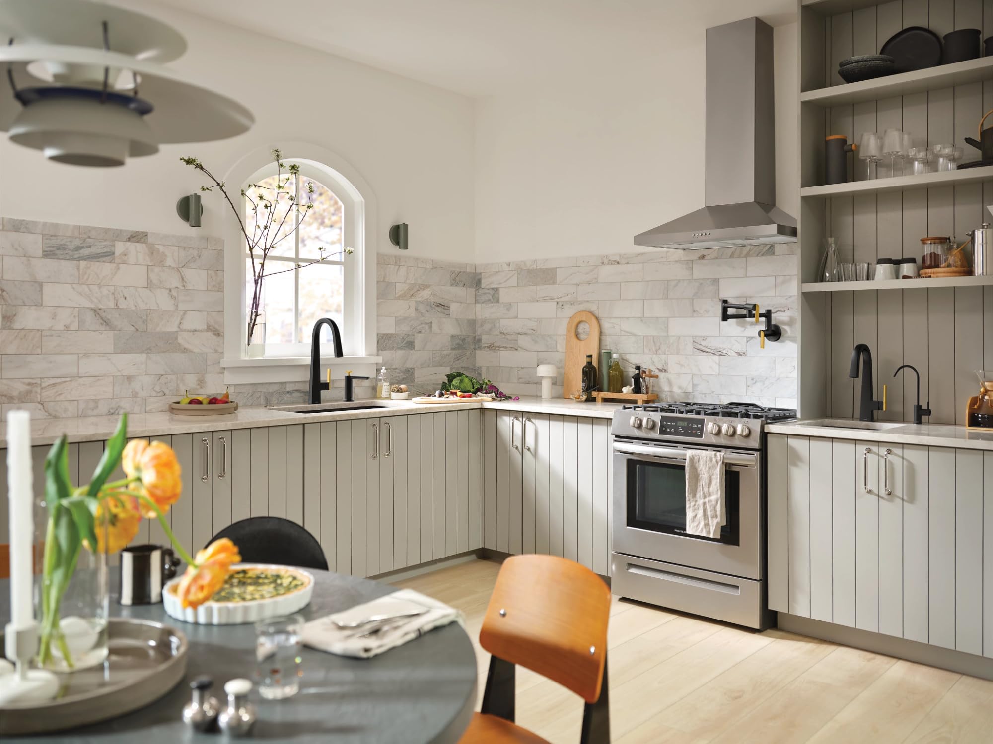 Matte black modern kitchen beverage faucet with slim spout installed at sink in kitchen with marble backsplash.