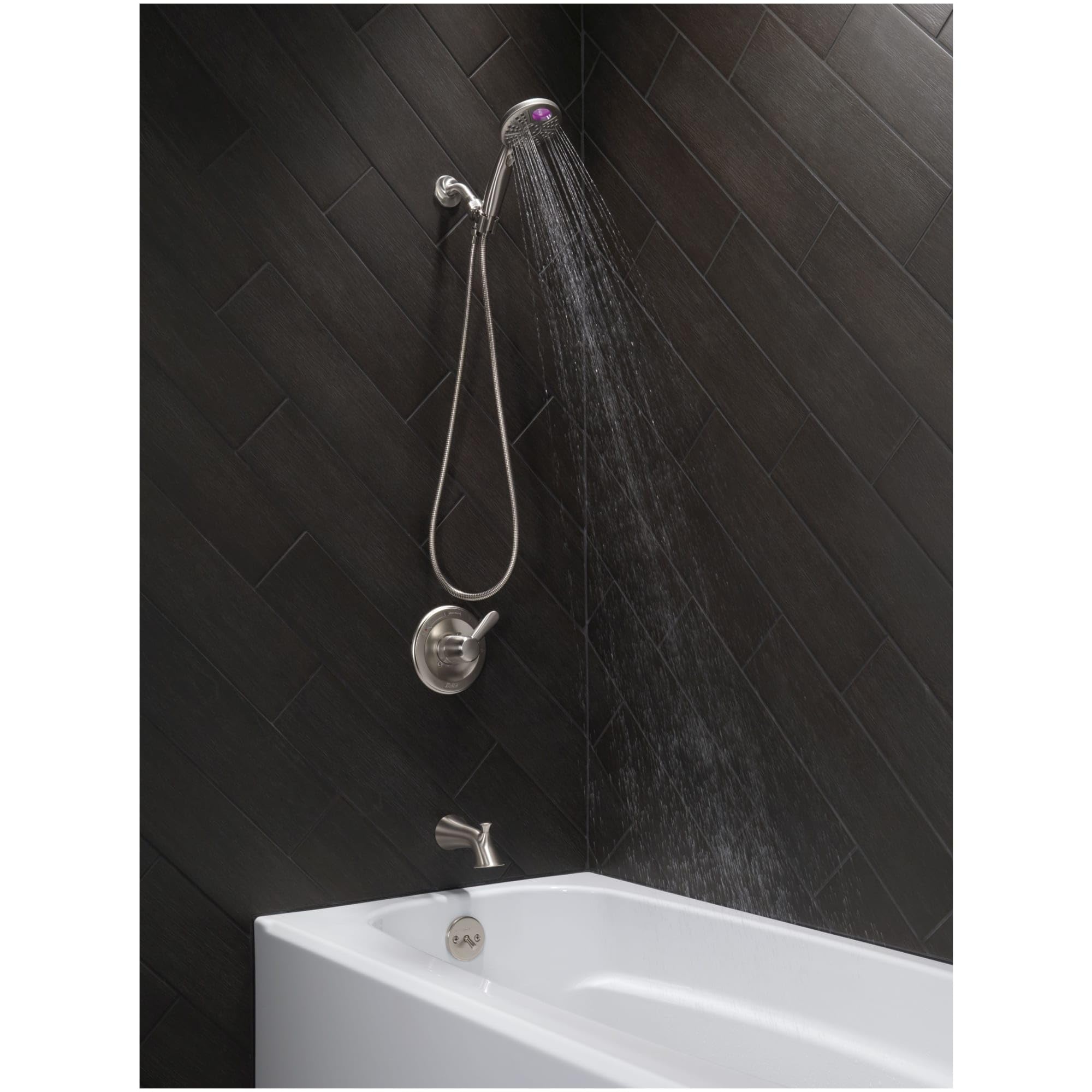 Polished nickel shower flange mounted on black tile wall with handheld showerhead and tub spout.