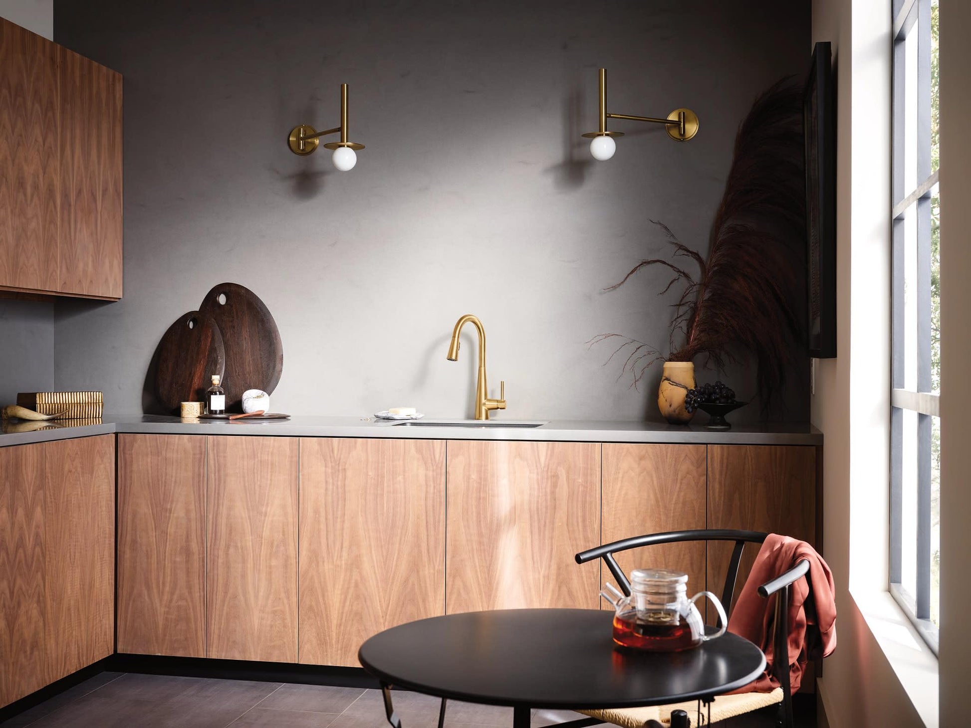 Brushed gold single-handle kitchen faucet with curved spout installed above sink in modern kitchen.
