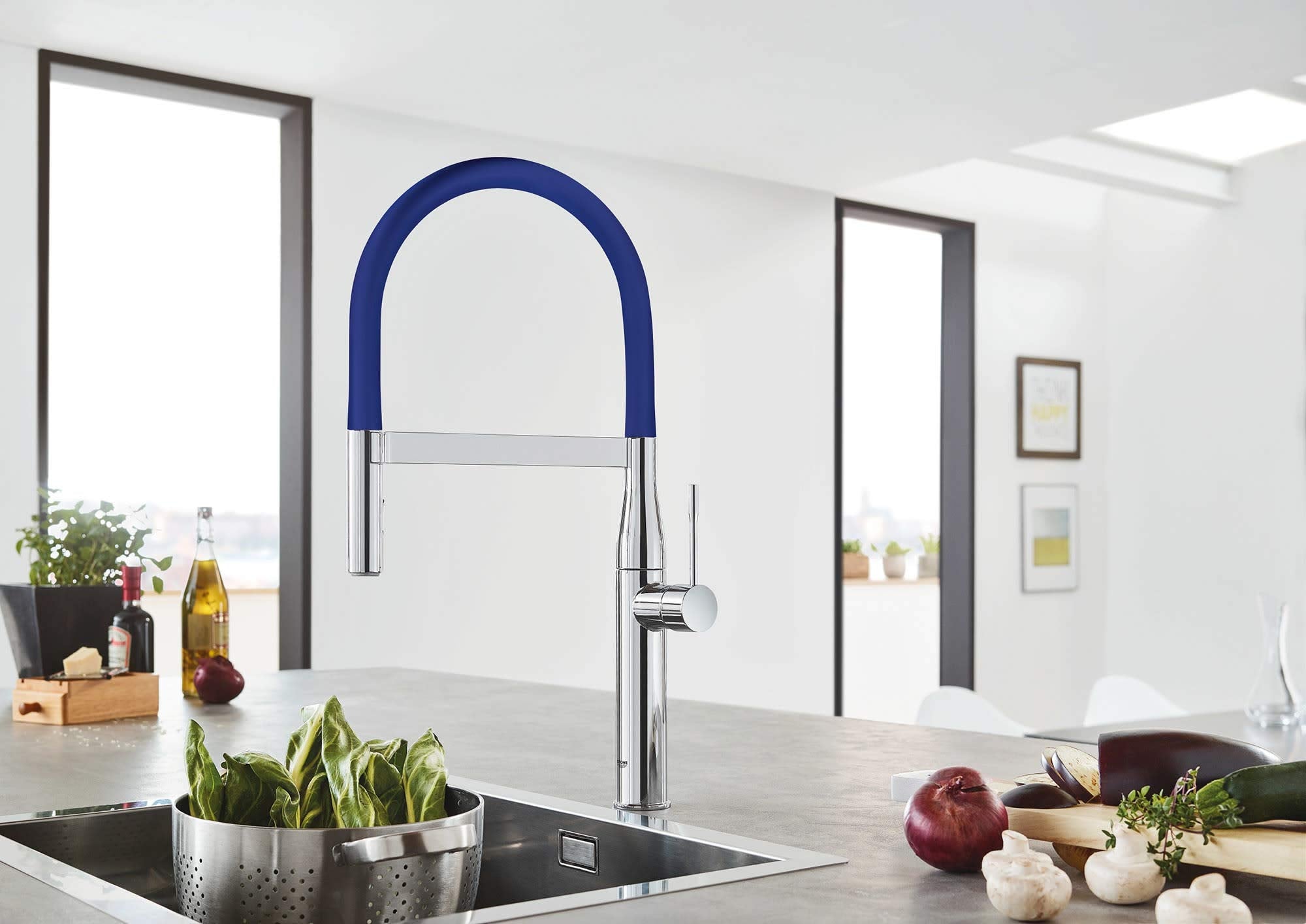 Chrome kitchen faucet with blue pull-down hose and high arched spout installed over sink.