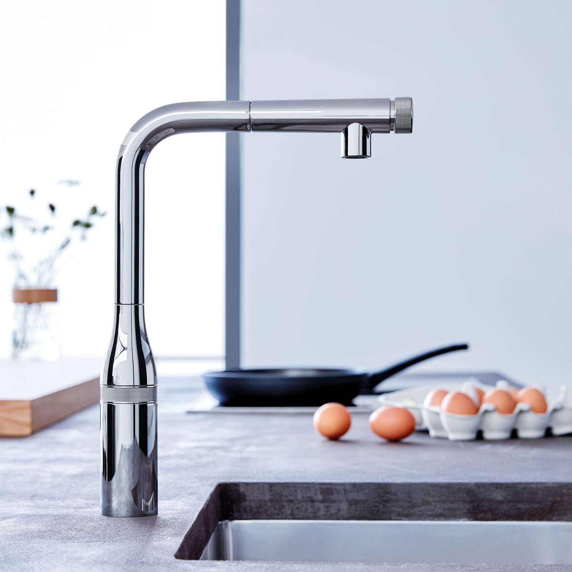 Chrome pull-out kitchen faucet with curved spout and single spray handle mounted above sink.