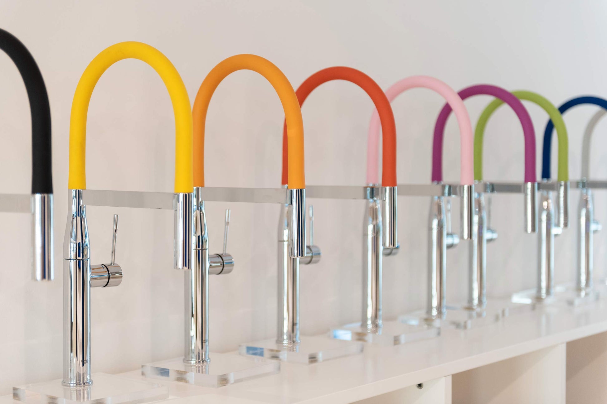 Chrome kitchen faucet with yellow flexible hose spout, displayed among other color variants.