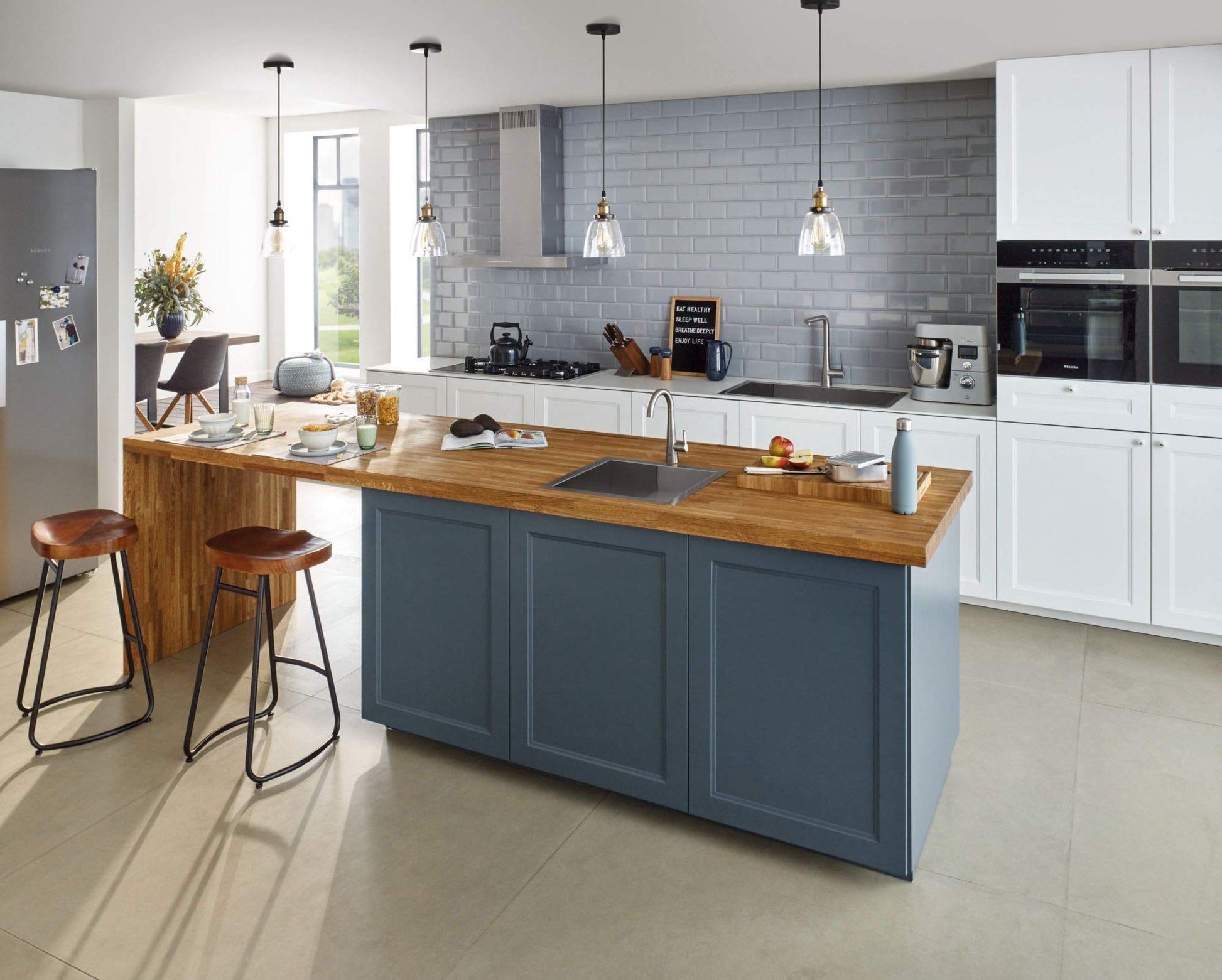 Chrome single-handle beverage faucet with thin spout installed on kitchen island countertop next to sink.