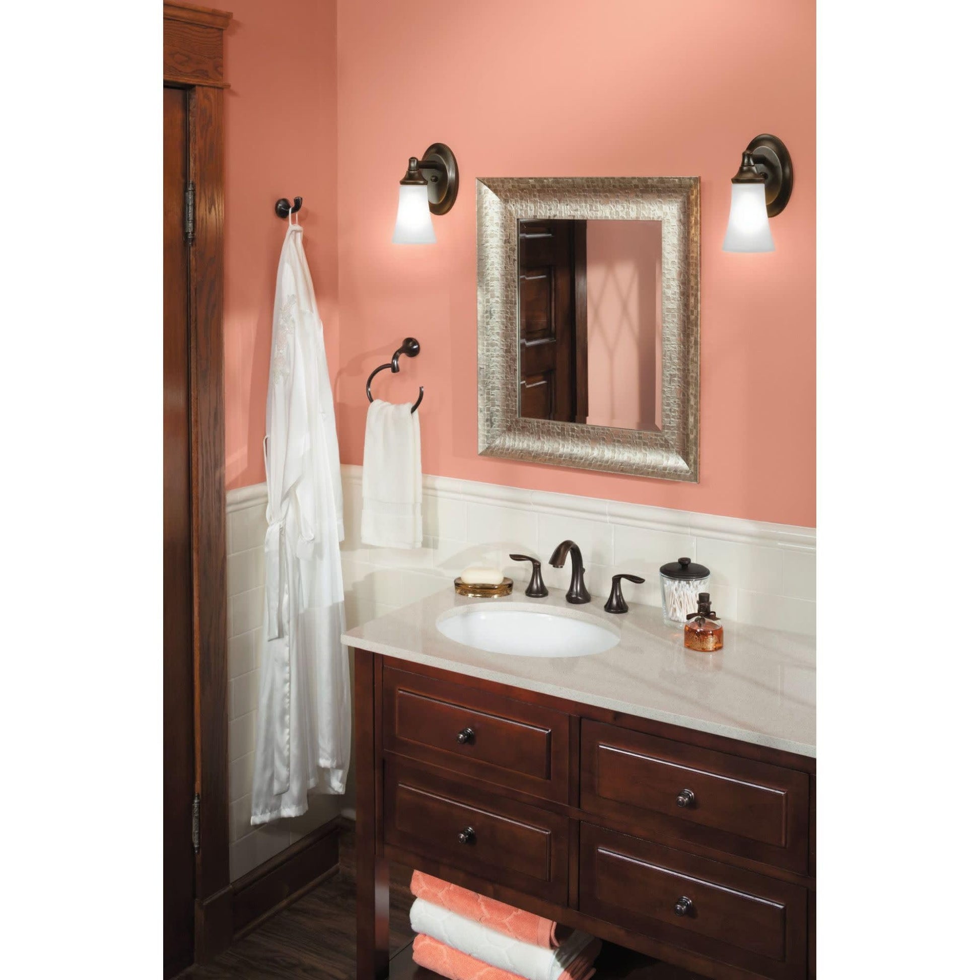 Oil-rubbed bronze vanity light fixture with frosted glass shade mounted above bathroom mirror.