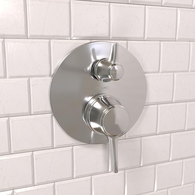 Chrome pressure balance valve trim with round escutcheon and dual lever handles mounted on white subway tile wall.