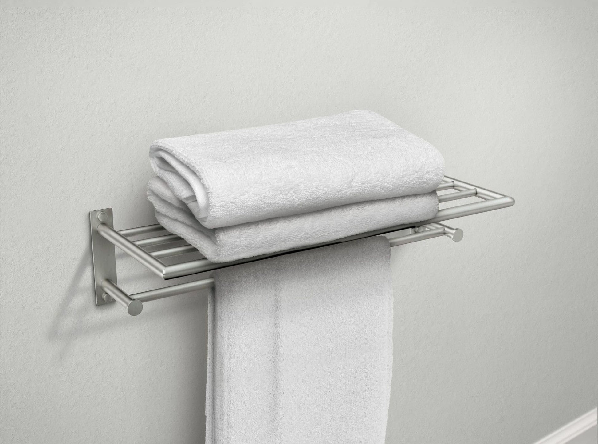 Brushed nickel bathroom shelf with towel bar holding folded white towels and one draped towel.