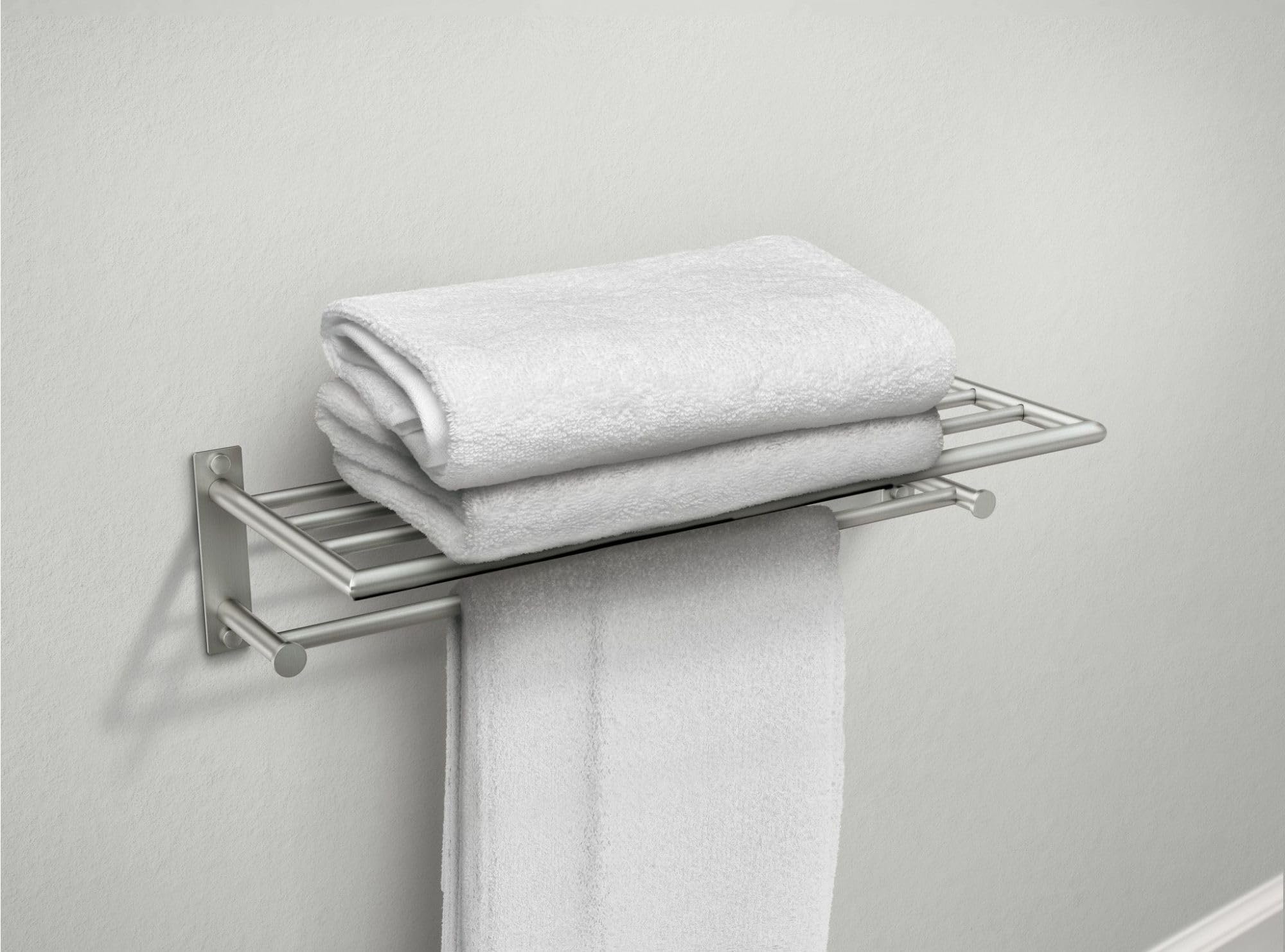 Brushed nickel bathroom shelf with towel bar holding folded white towels and one draped towel.