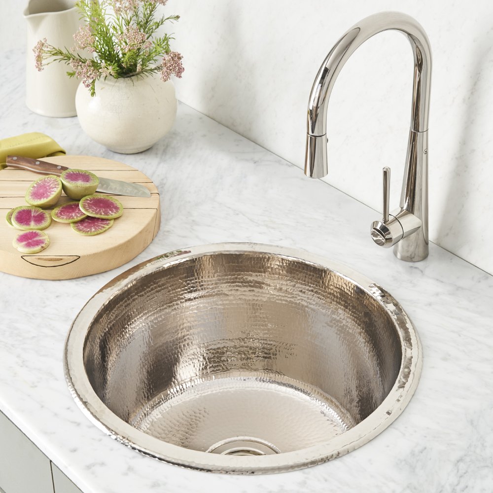 Polished nickel round bar sink with hammered texture and matching pull-down faucet on marble countertop.