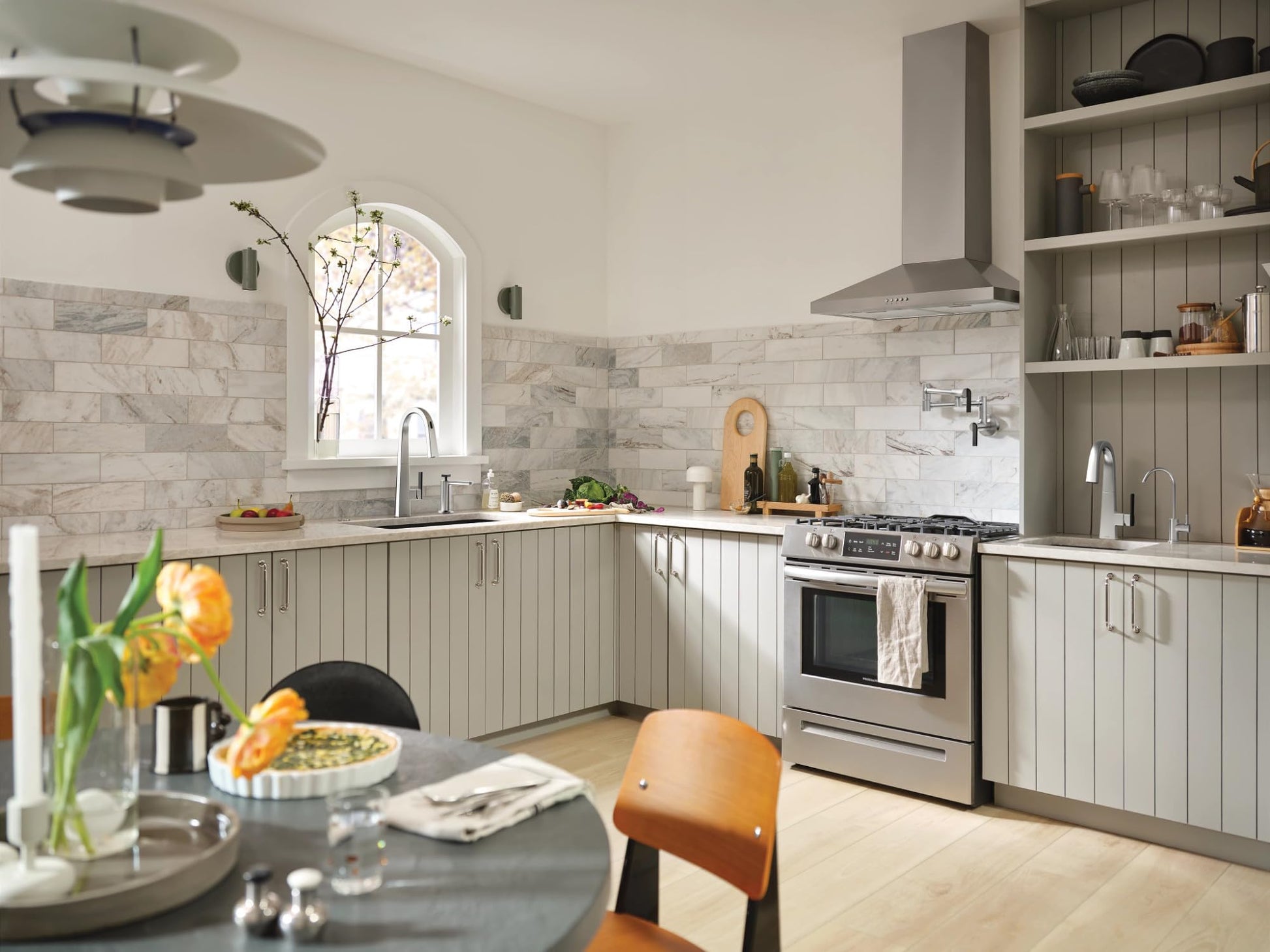 Chrome single-handle bar faucet with high arc spout installed in kitchen sink with marble backsplash.