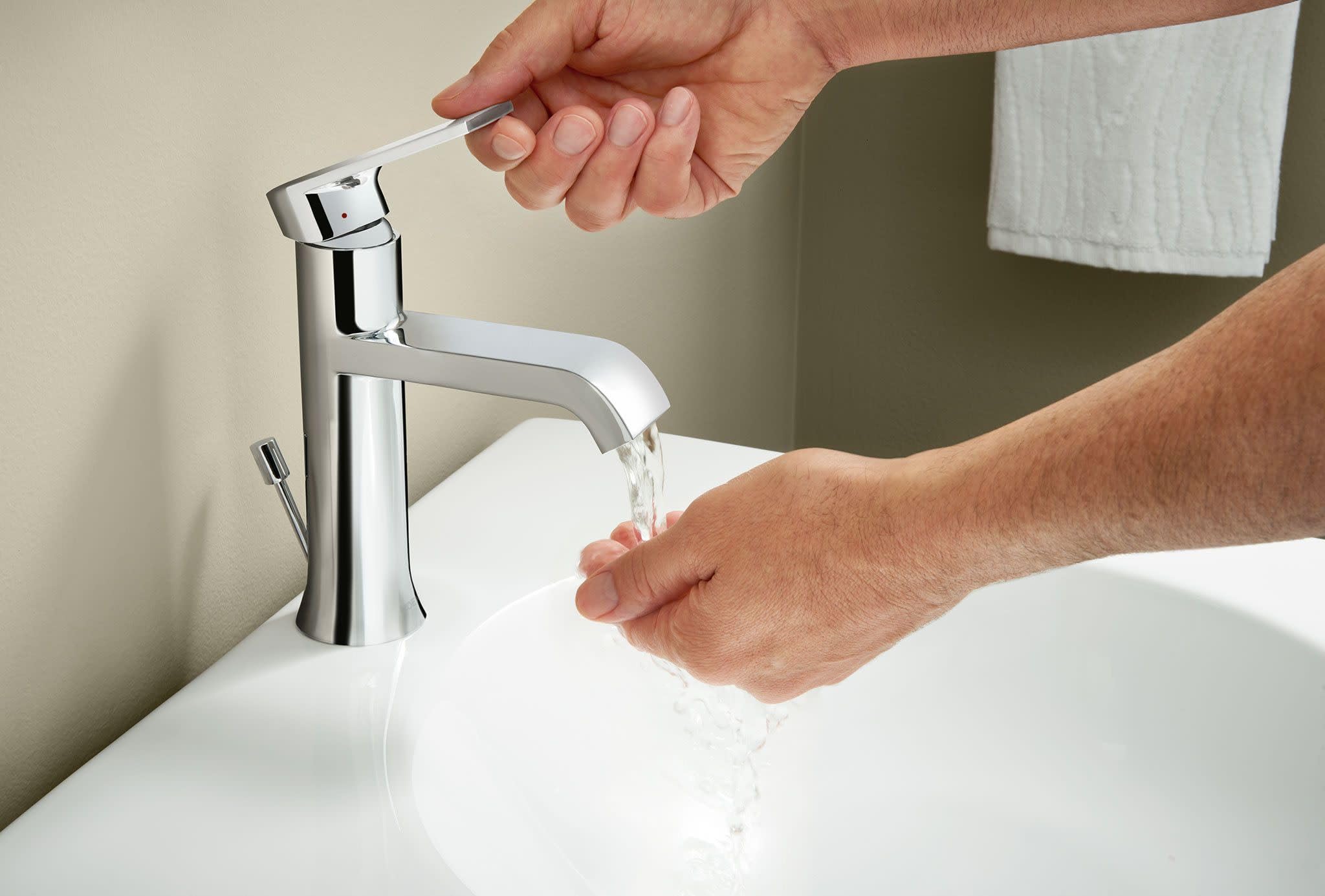 Chrome single-handle bathroom faucet with curved spout installed on white sink with water running.