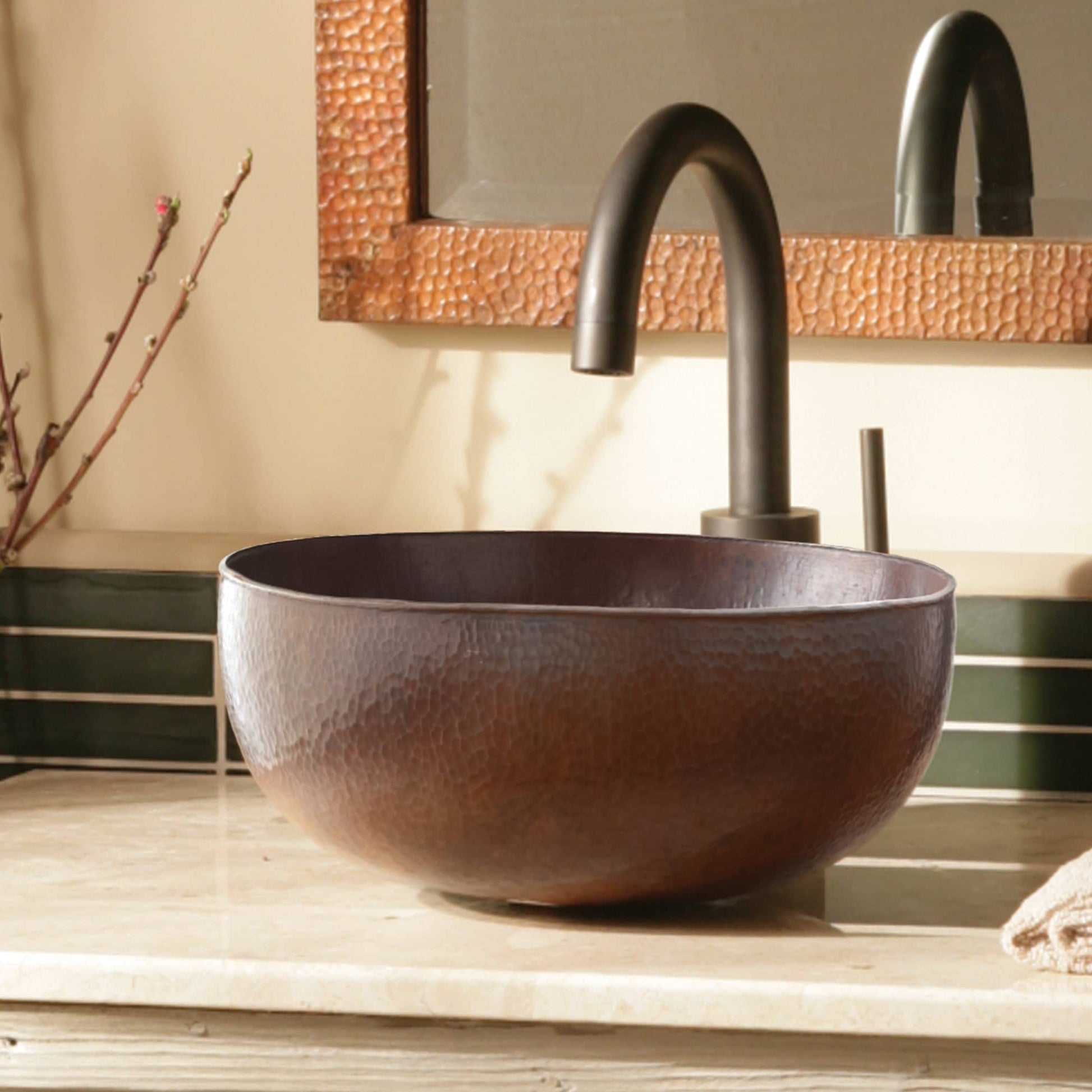 Hammered copper vessel sink with textured surface and curved black faucet on bathroom counter.