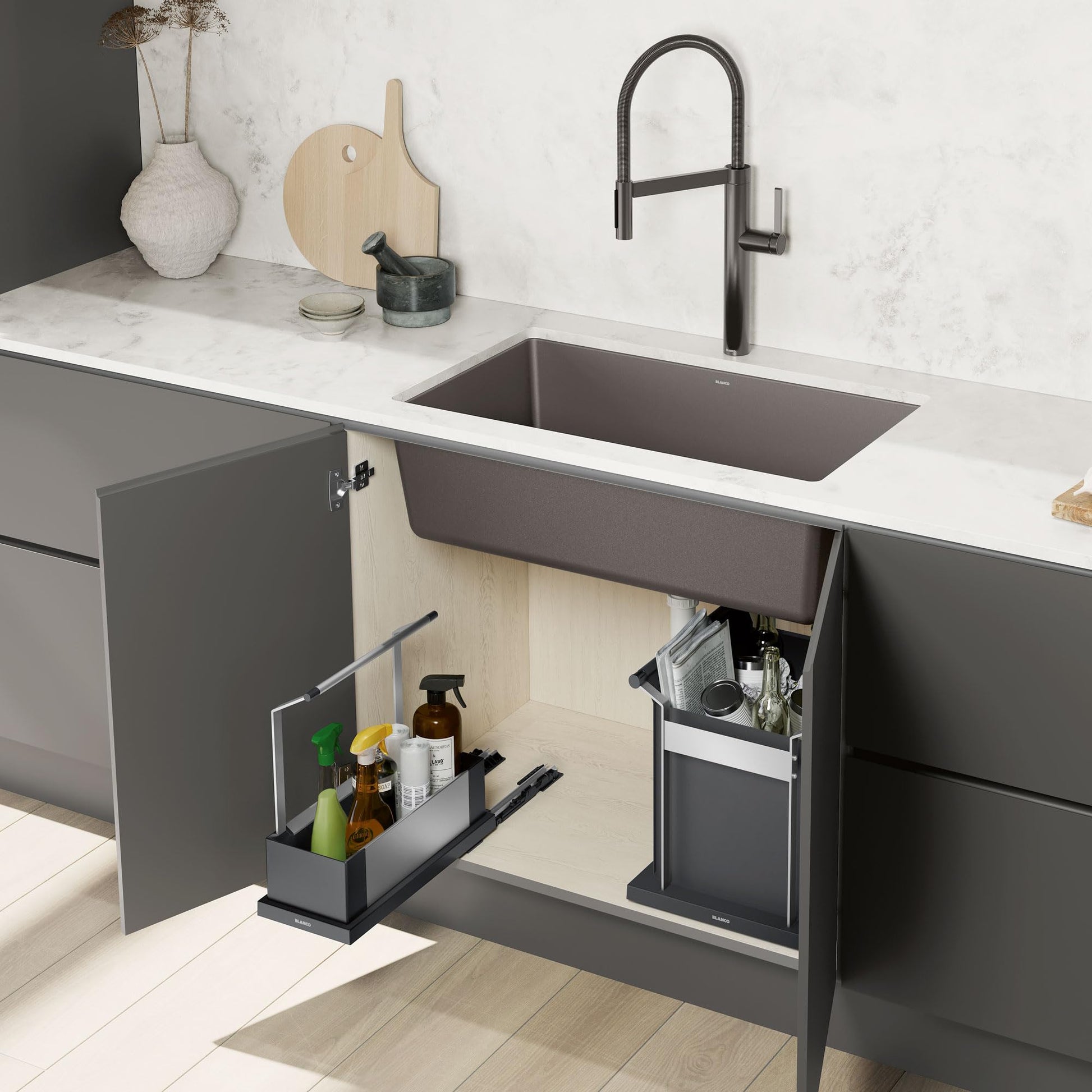 Black pull-out storage caddy installed under kitchen sink with bottles and cleaning supplies inside.