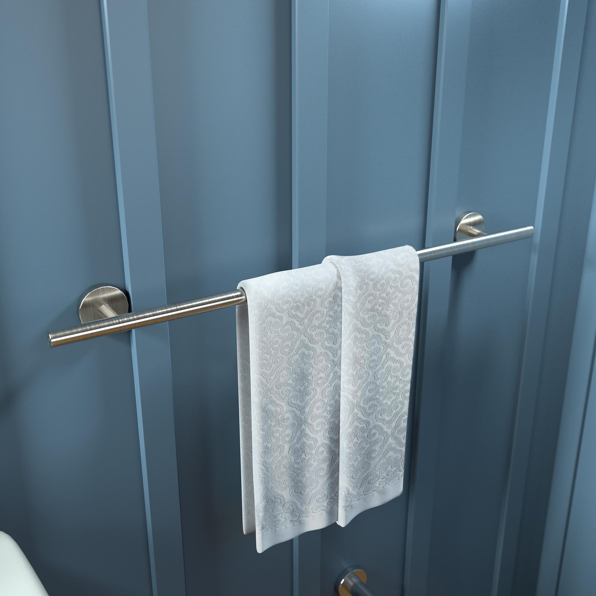 Brushed nickel towel bar mounted on blue wall with white patterned towel draped over it.