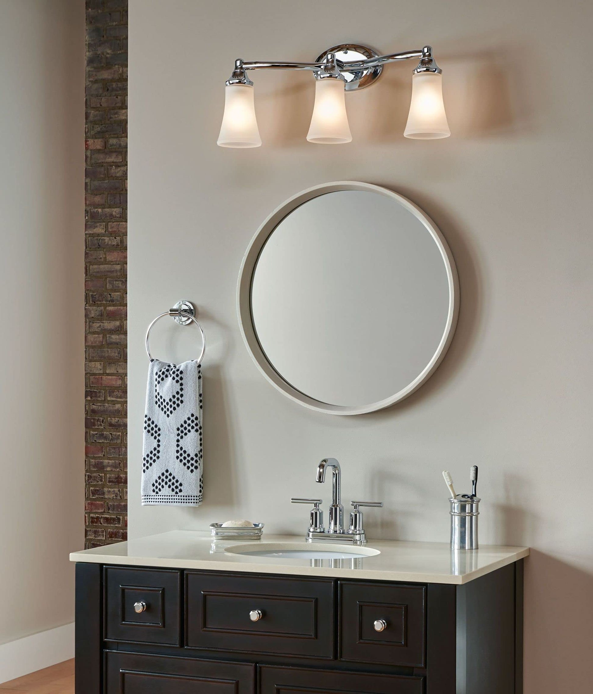 Polished chrome towel ring mounted on bathroom wall with white patterned hand towel draped over it.