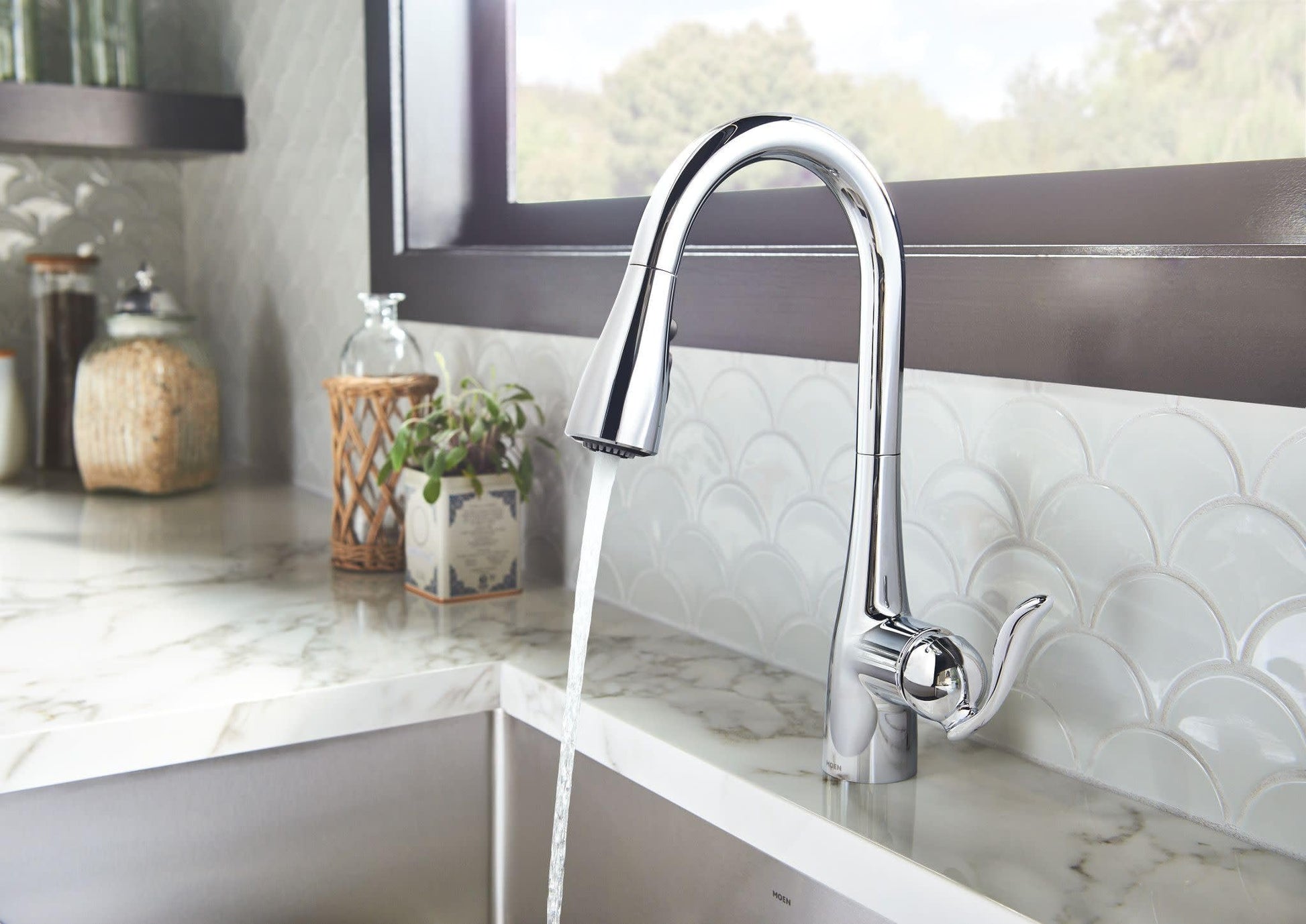 Chrome kitchen faucet with single handle and pull-down sprayer installed in marble countertop sink.