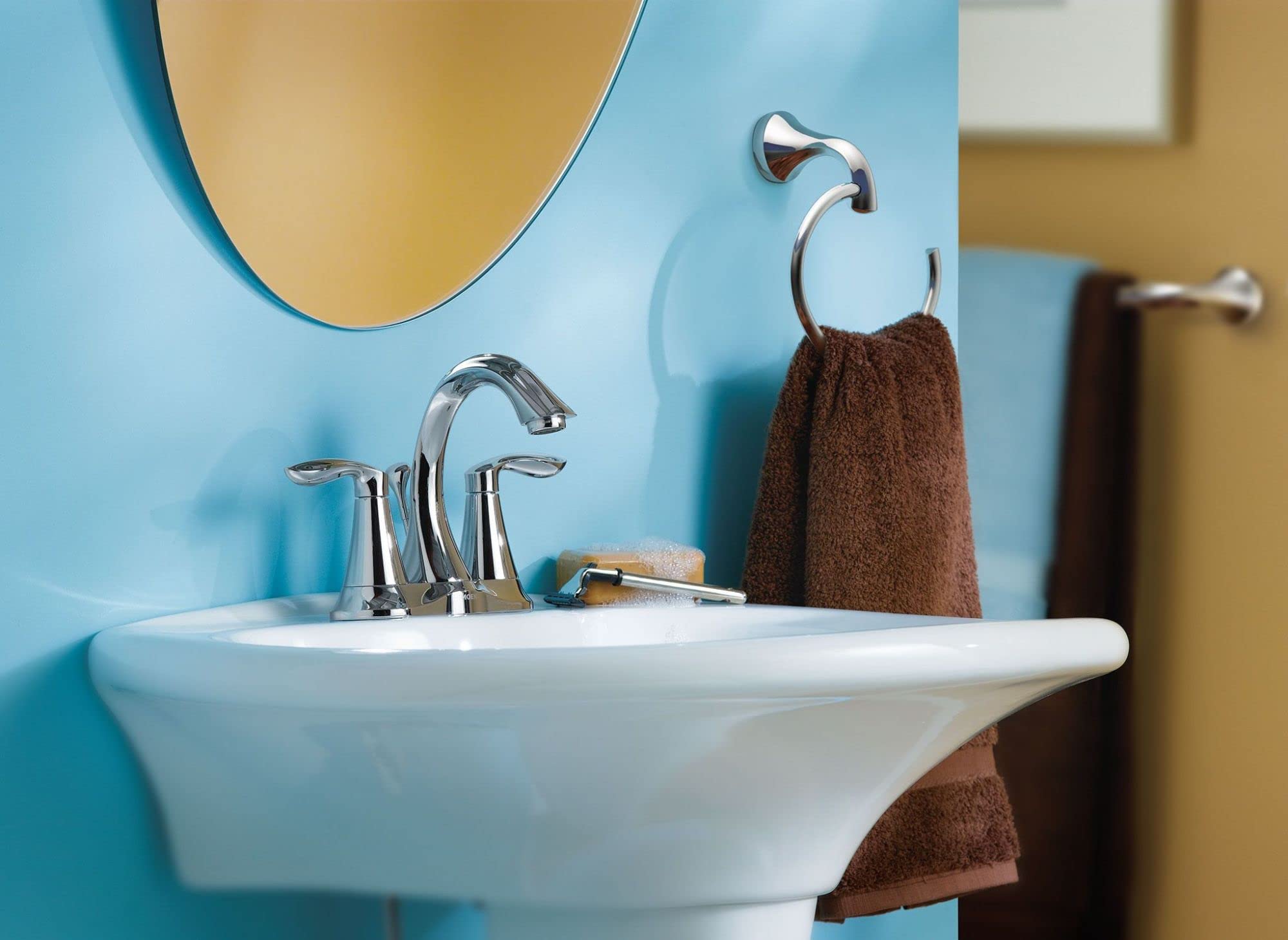 Chrome towel bar mounted on blue bathroom wall with brown towel hanging from curved hook.