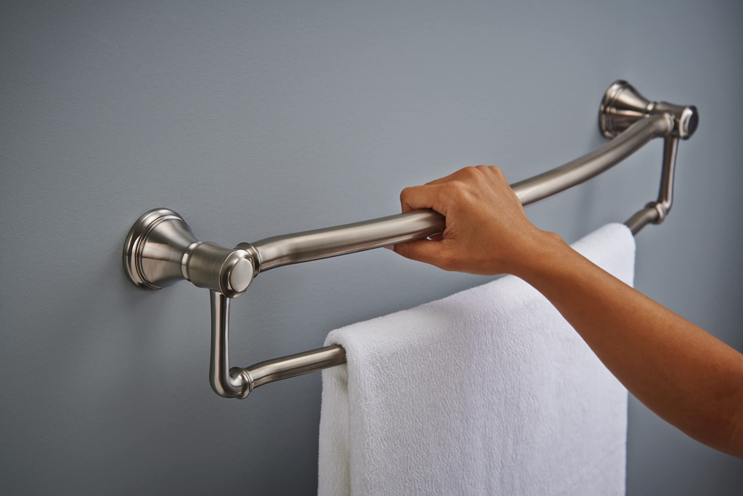 Brushed stainless steel towel bar with assist grab handle mounted on gray wall, white towel draped over lower bar.
