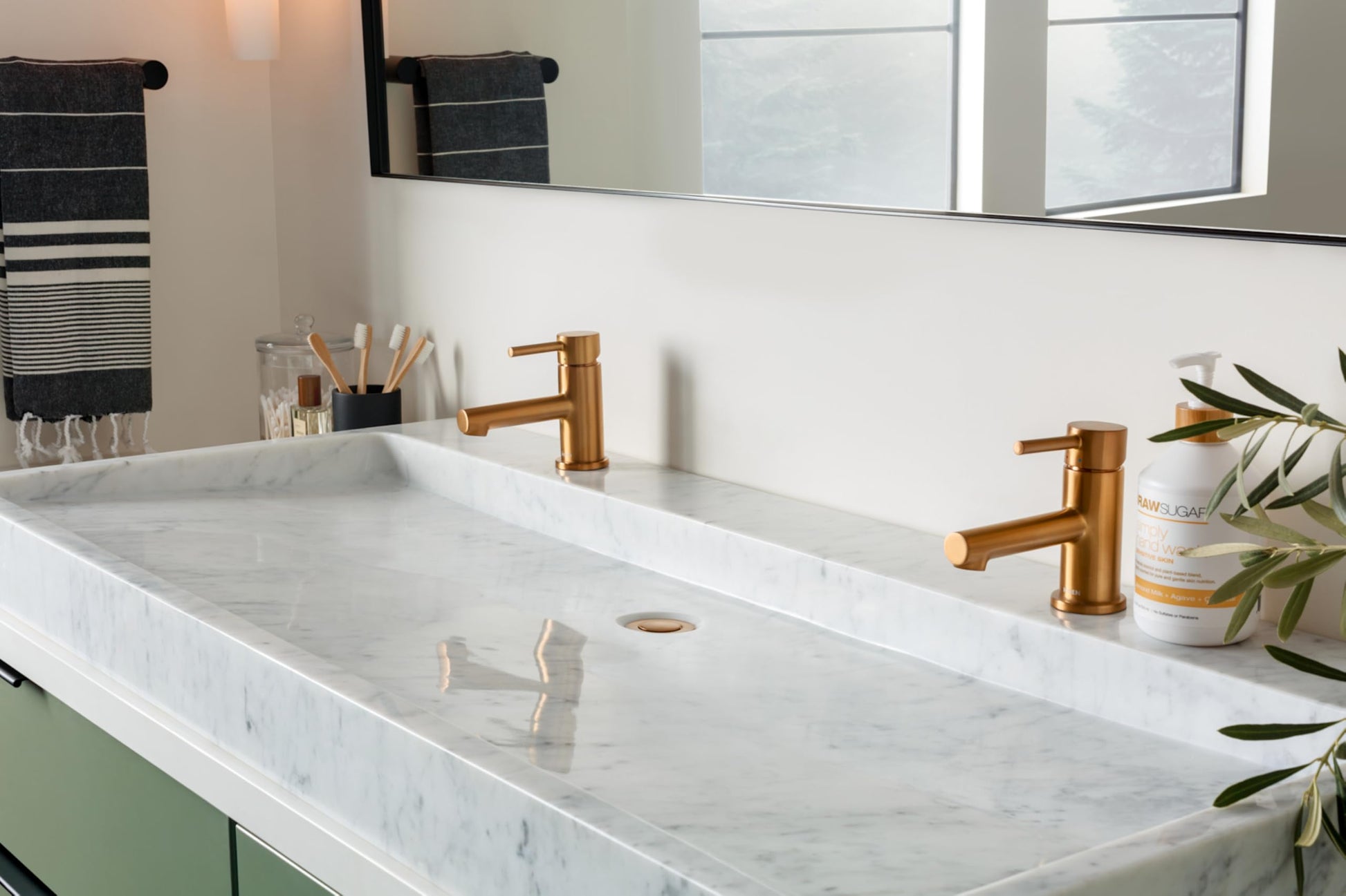 Brushed nickel single-handle low-arc bathroom faucet installed on white marble countertop with two sink basins.