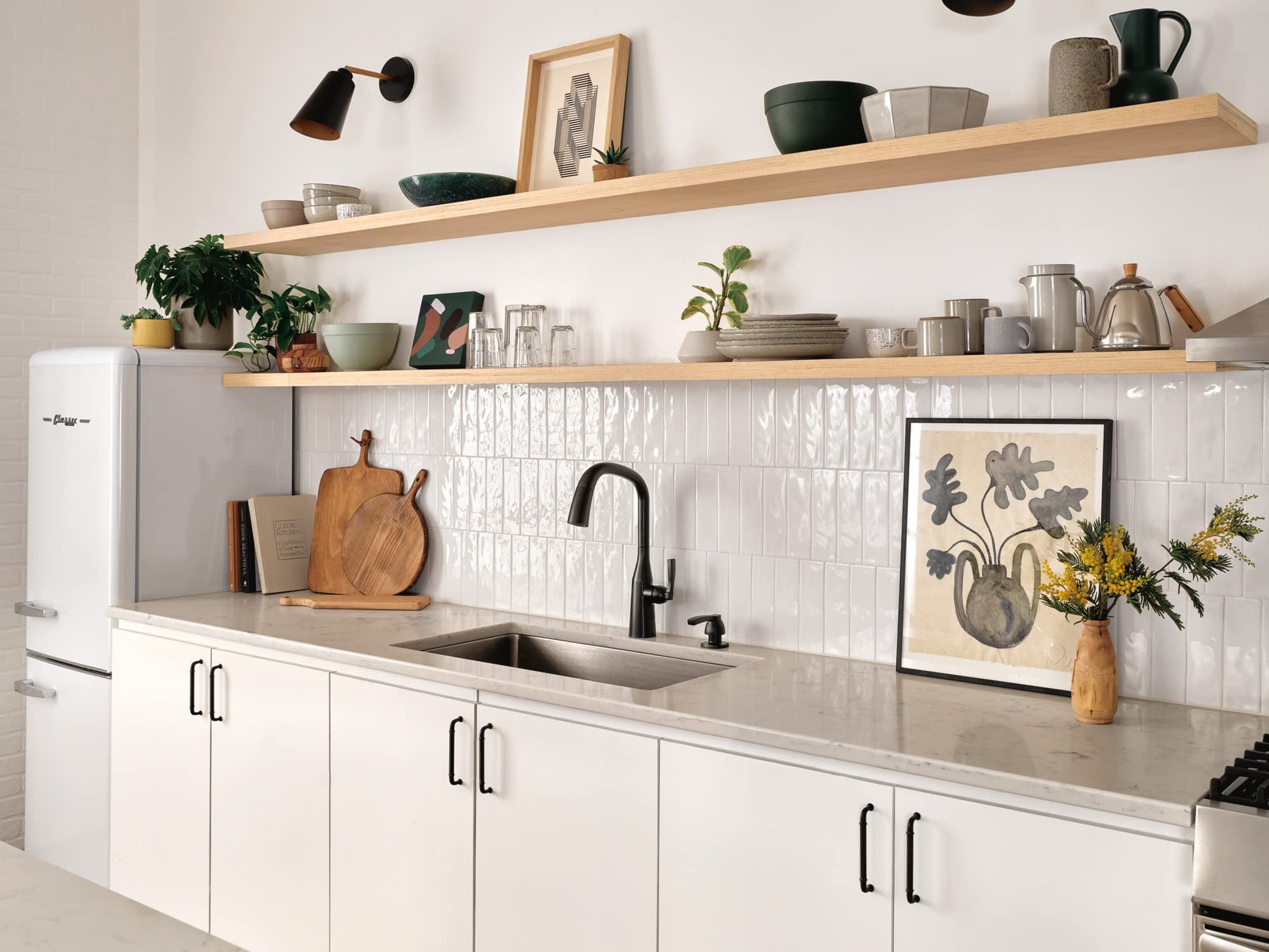 Matte black soap and lotion dispenser mounted on white subway tile backsplash next to kitchen sink faucet.