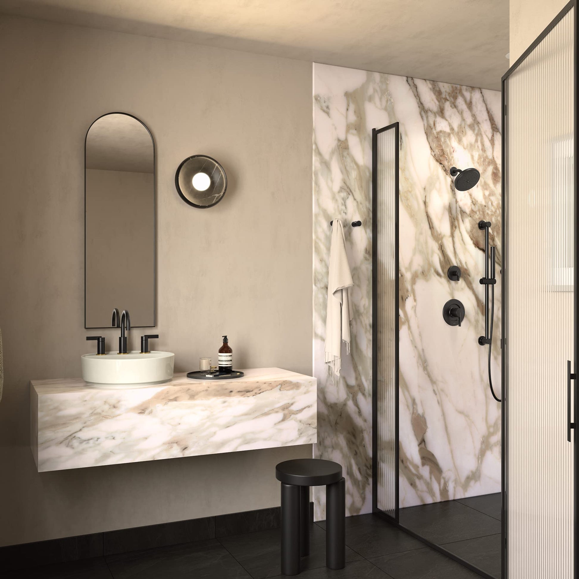 Matte black single-handle shower trim kit with round trim ring mounted on marble tile shower wall.