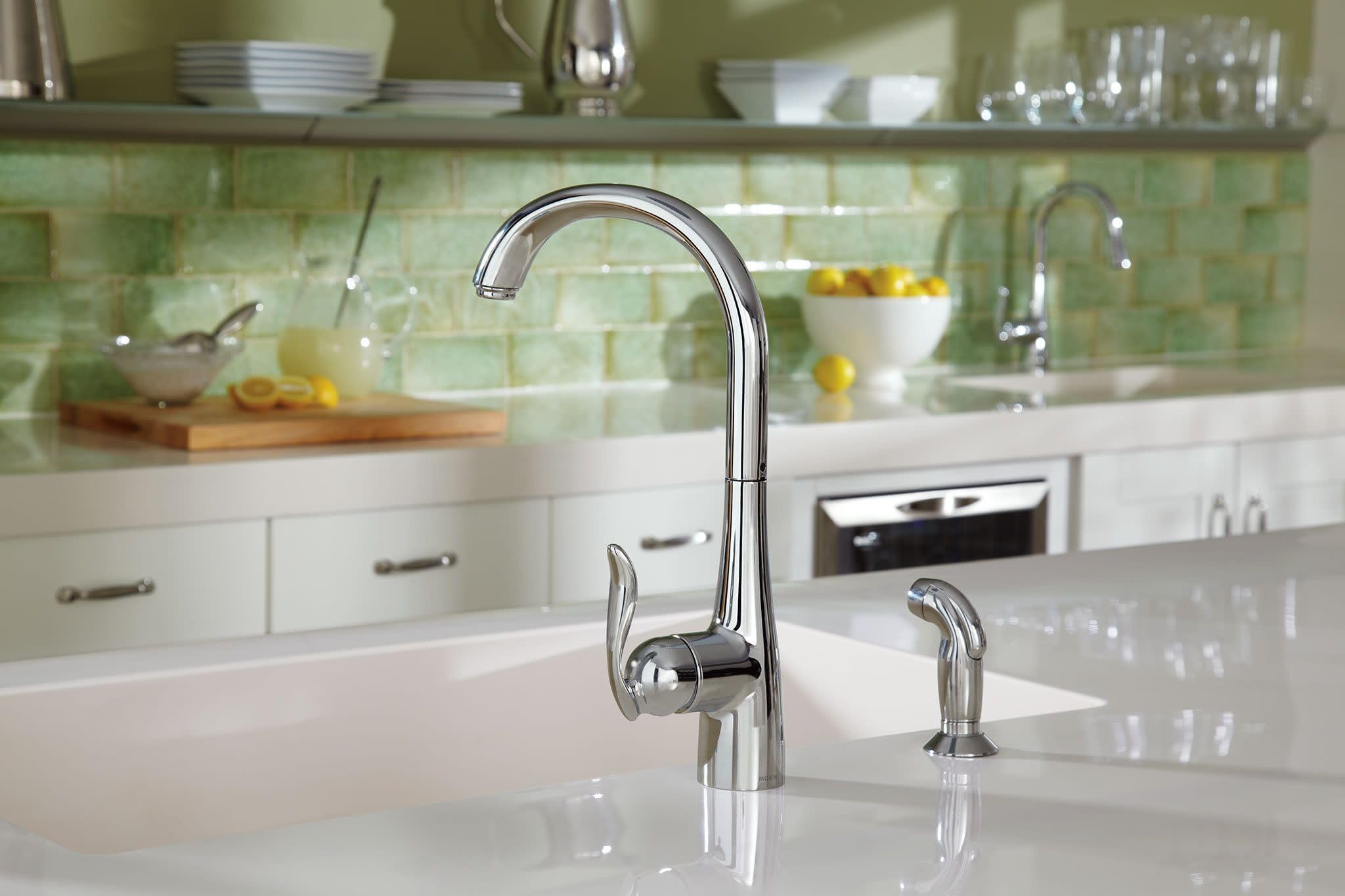 Polished stainless steel kitchen faucet with high arc spout, single handle, and side spray mounted on white countertop.