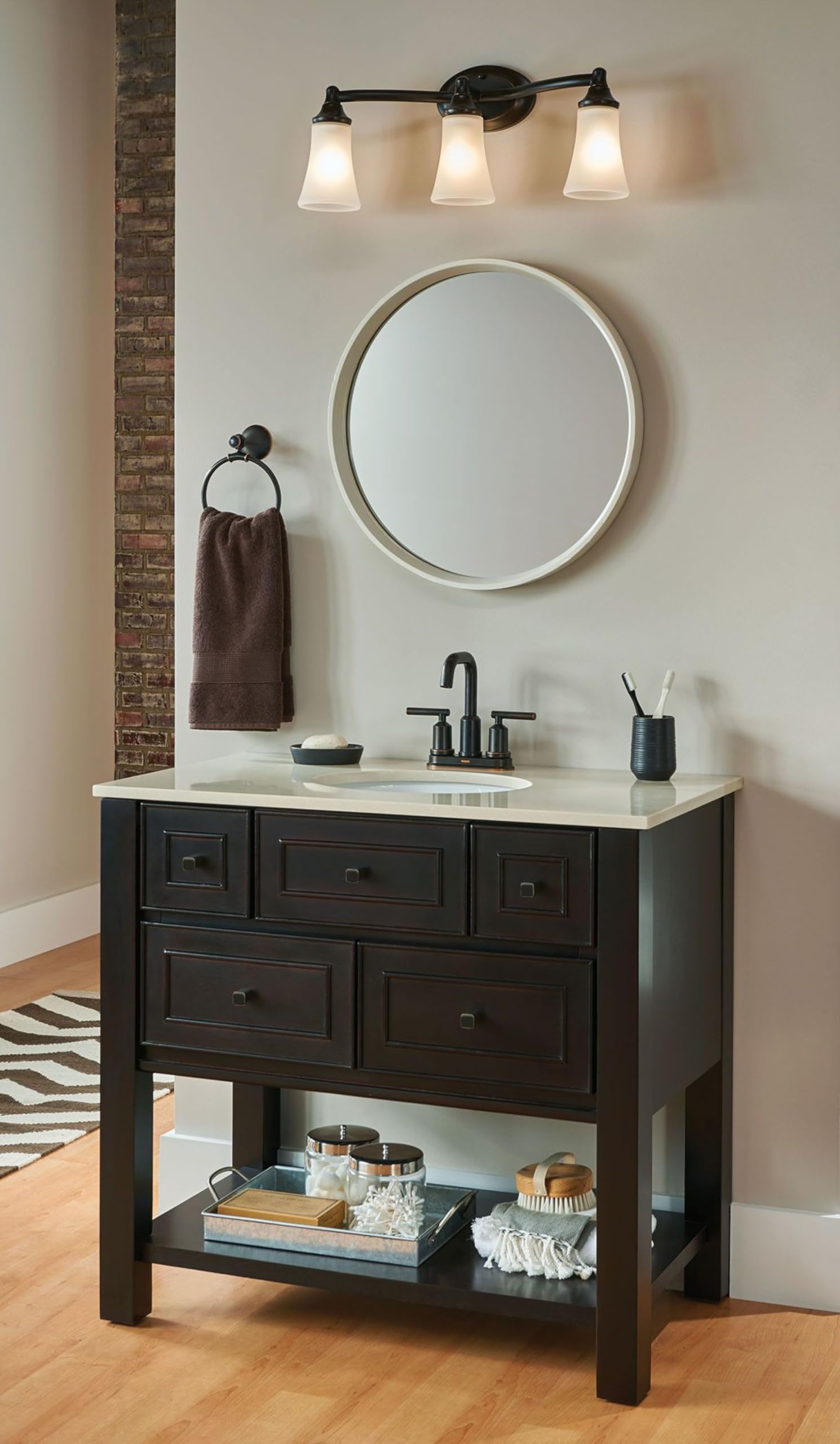 Oil-rubbed bronze bathroom vanity light fixture with three frosted glass shades mounted above a sink.
