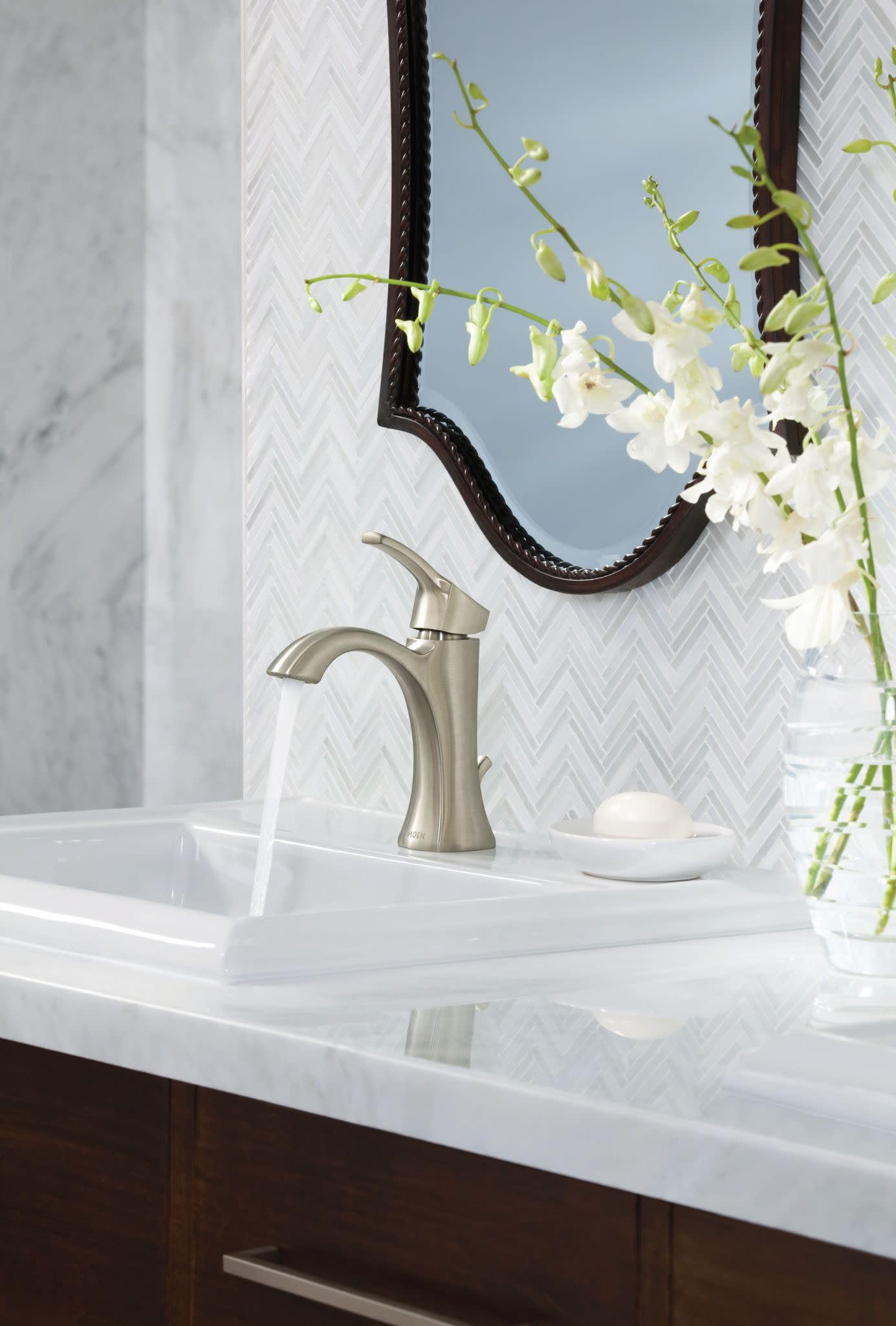 Brushed nickel single-handle bathroom faucet with high arc spout installed on white countertop sink.