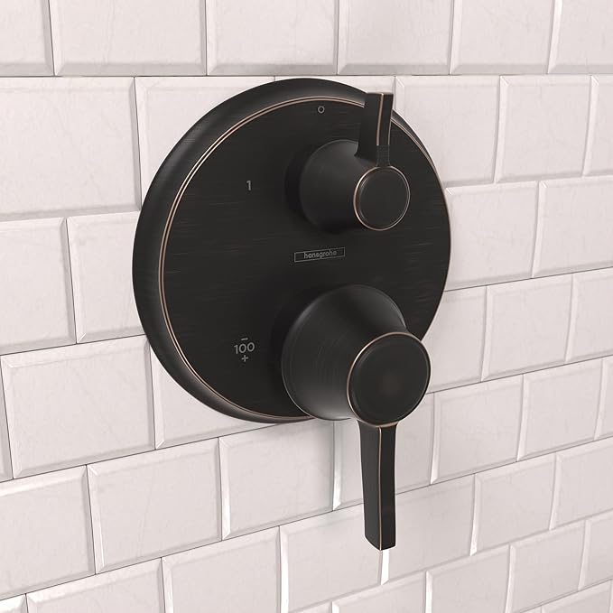 Round rubbed bronze thermostatic shower trim with temperature control dial and diverter handle mounted on white tile.