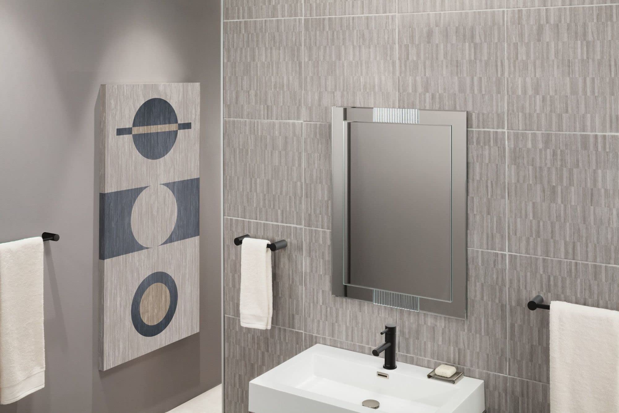 Black towel bar mounted on gray tile bathroom wall above white sink.