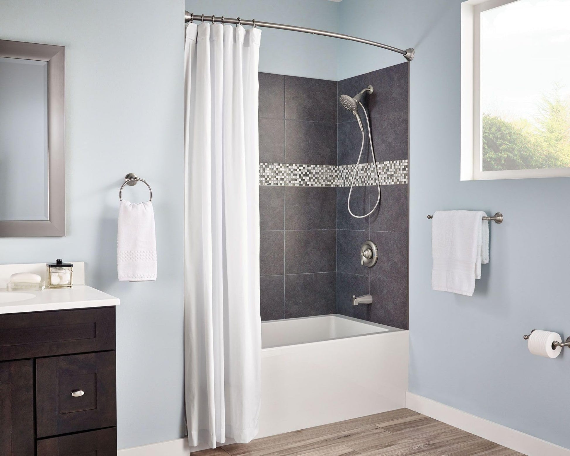 Brushed nickel wall-mounted towel ring holding a white hand towel in a bathroom setting.