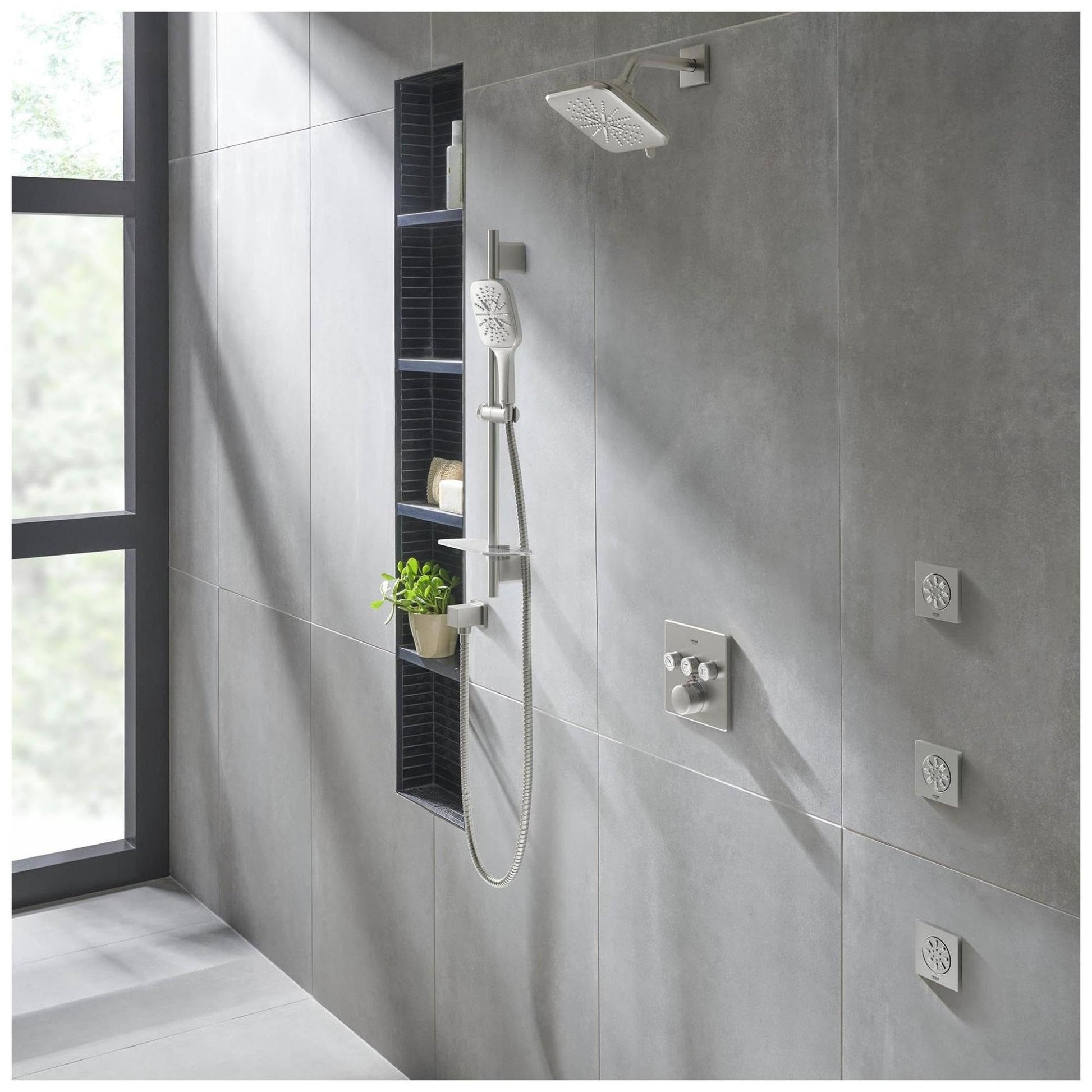 Matte black square shower arm mounted on gray tile wall above rainfall showerhead in modern bathroom.