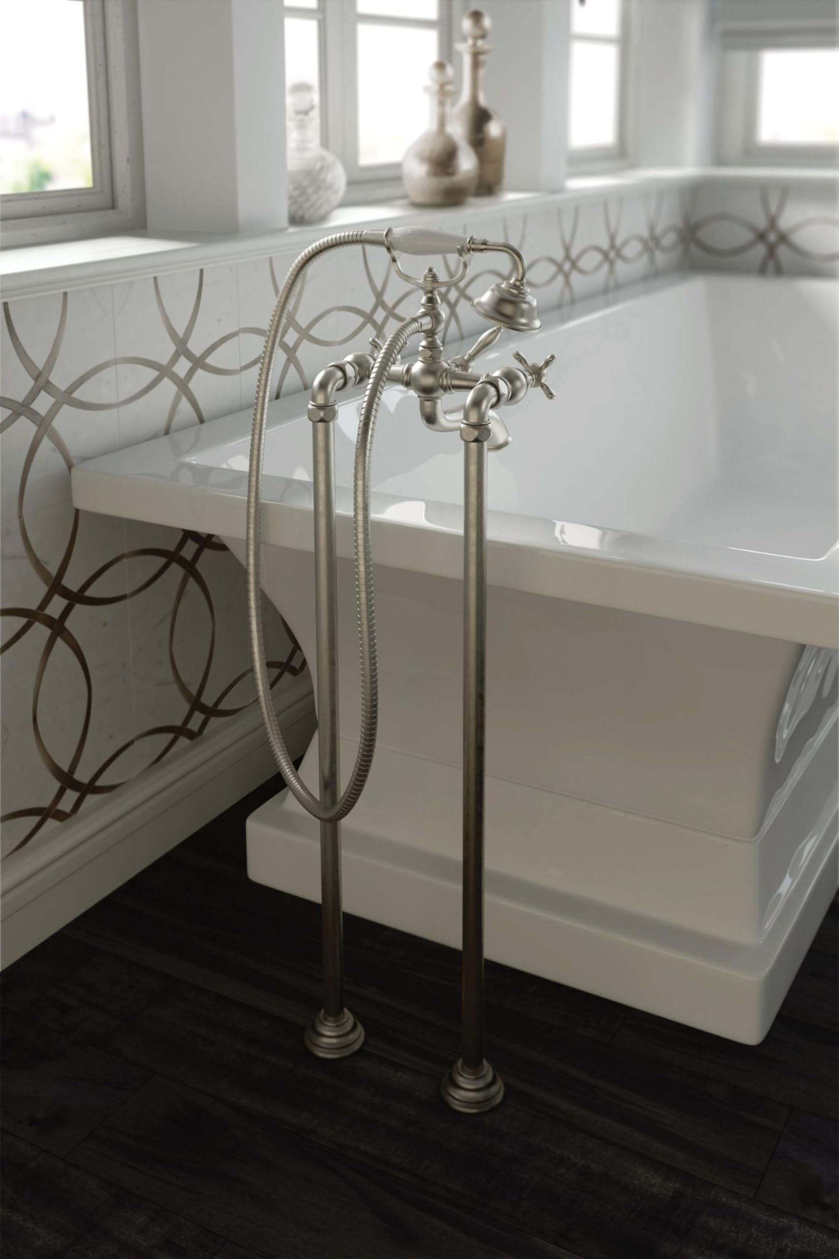 Brushed nickel freestanding tub filler with two handles, curved spout, and flexible hose next to white bathtub.