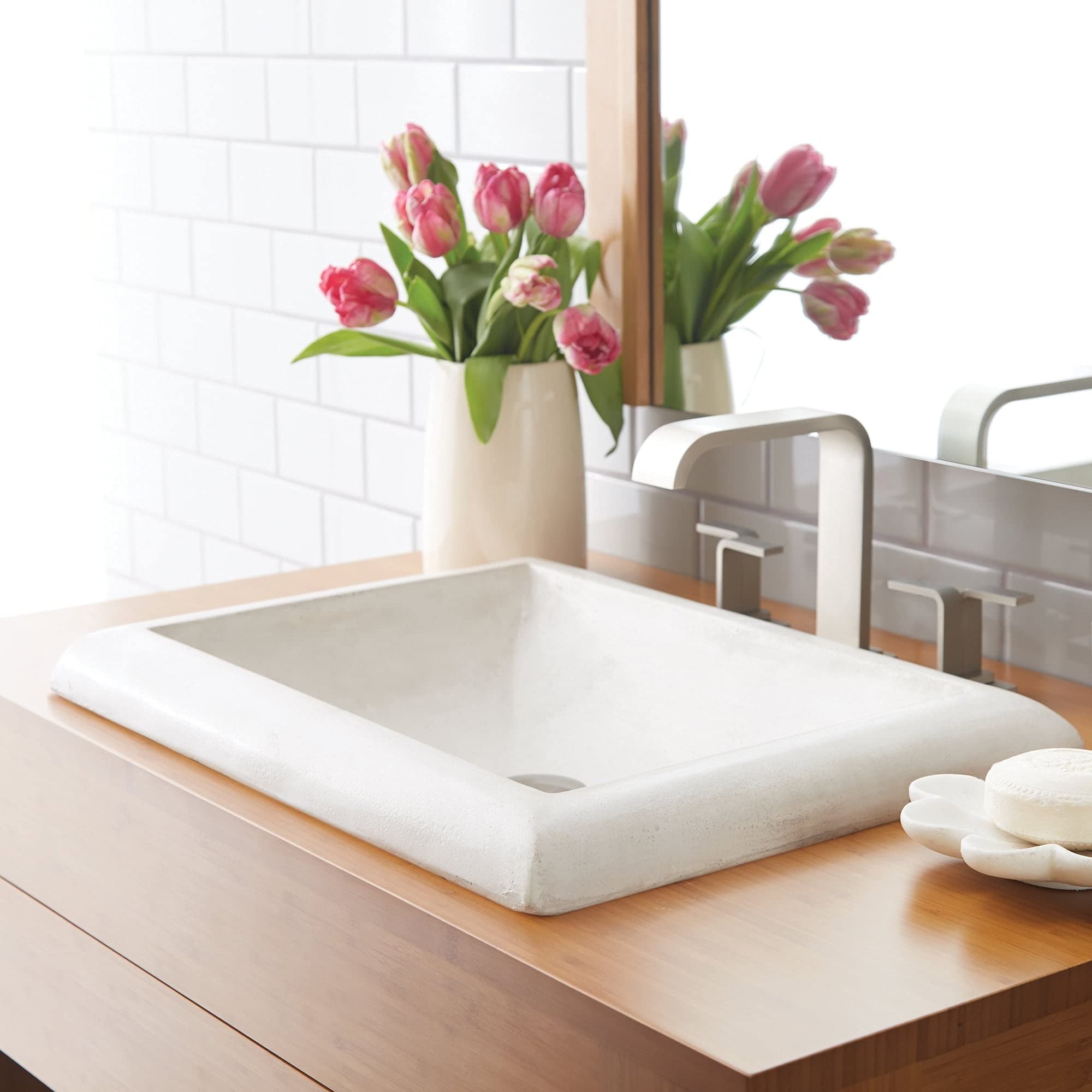 Rectangular ash-colored bathroom sink with rounded edges on wooden vanity next to mirror and faucet.