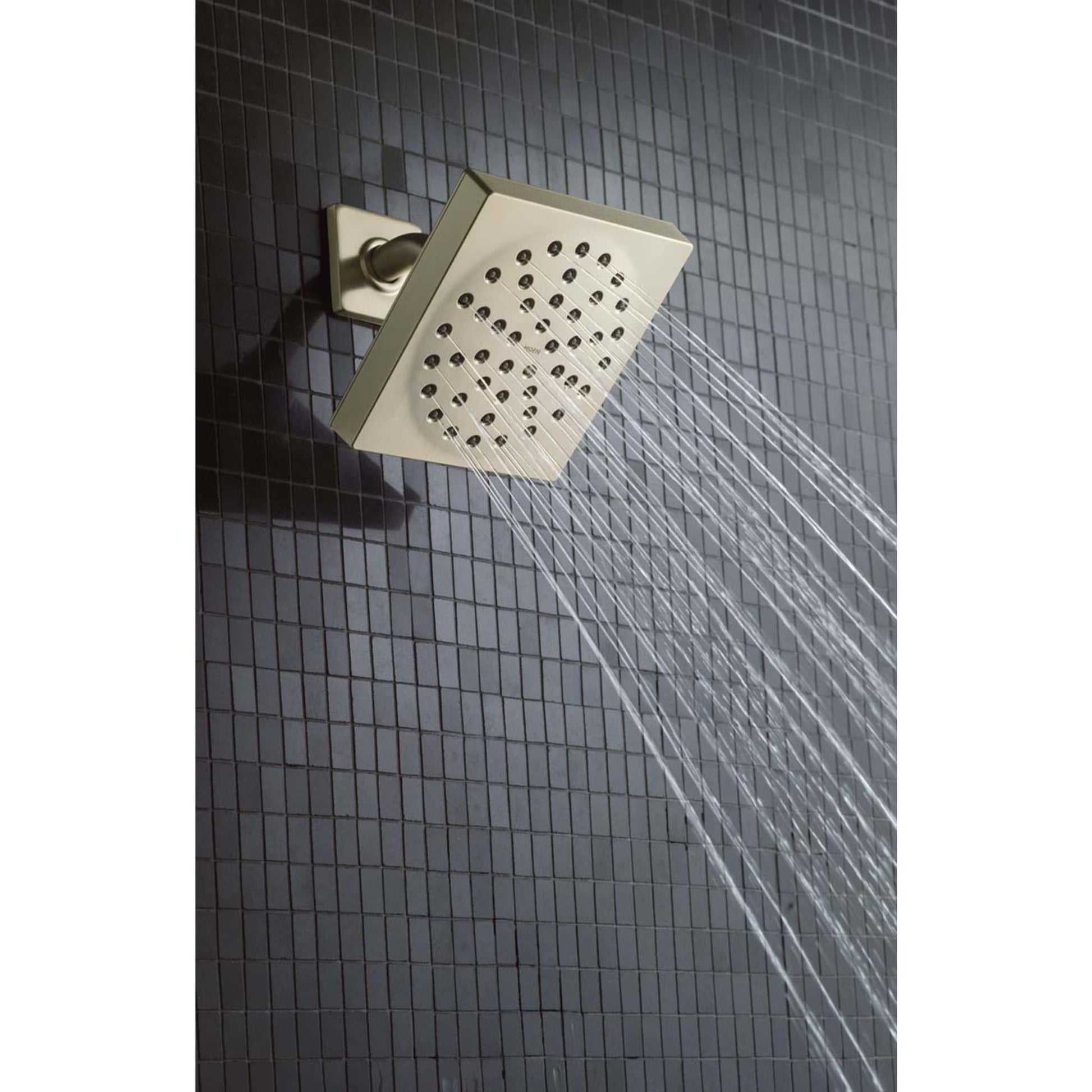Matte black square showerhead with multiple spray holes mounted on tiled shower wall with water flowing downward.